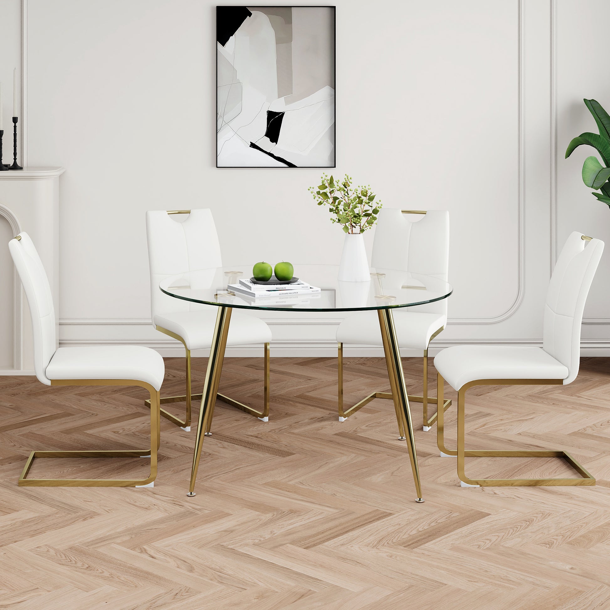 Round glass dining table with four white upholstered chairs featuring gold metal legs