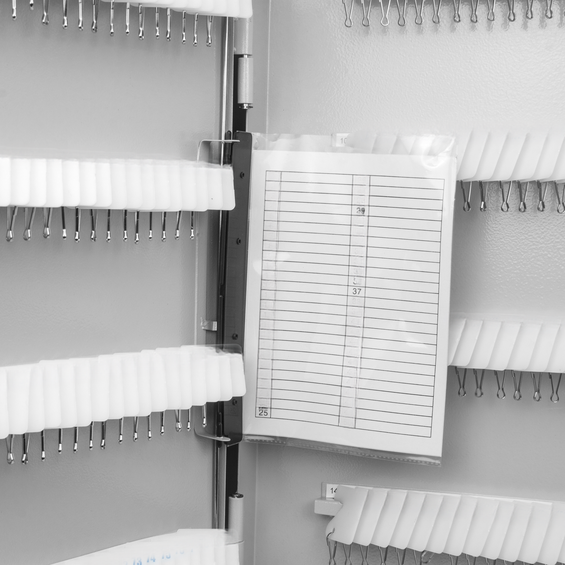 Gray metal key organizer with rows of white hooks and a clear plastic index card holder