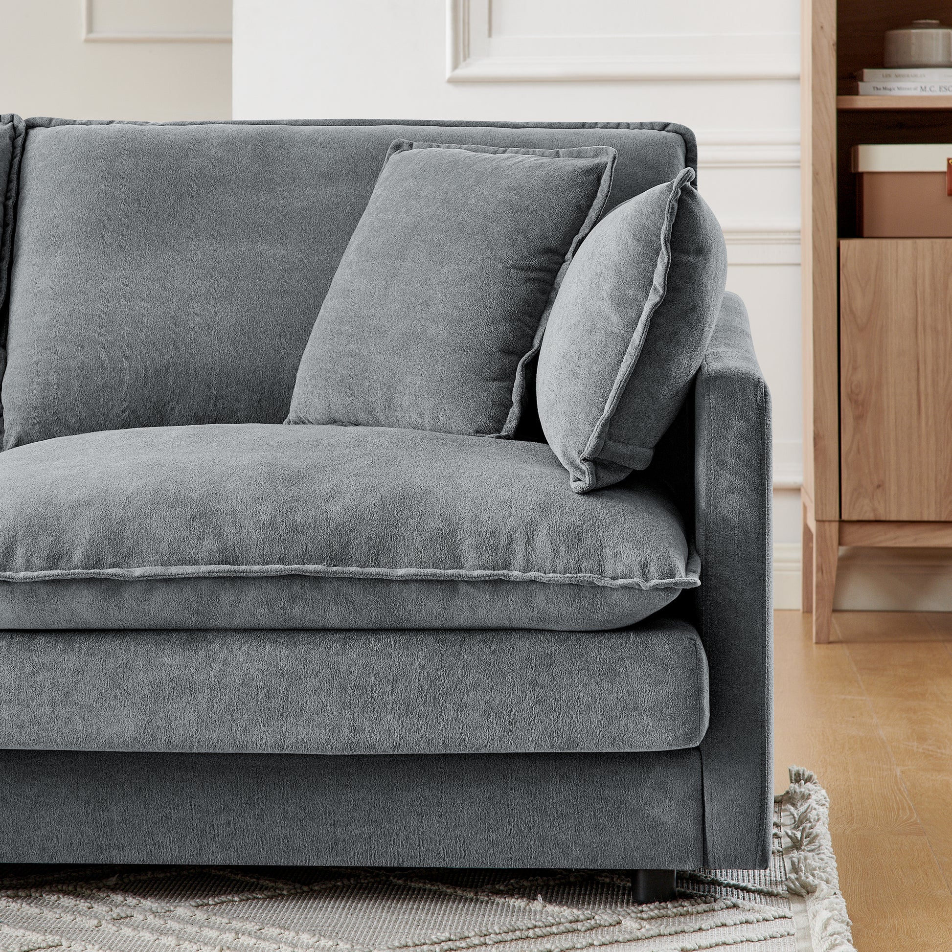 Deep grey plush fabric sofa with decorative piping and accent pillows