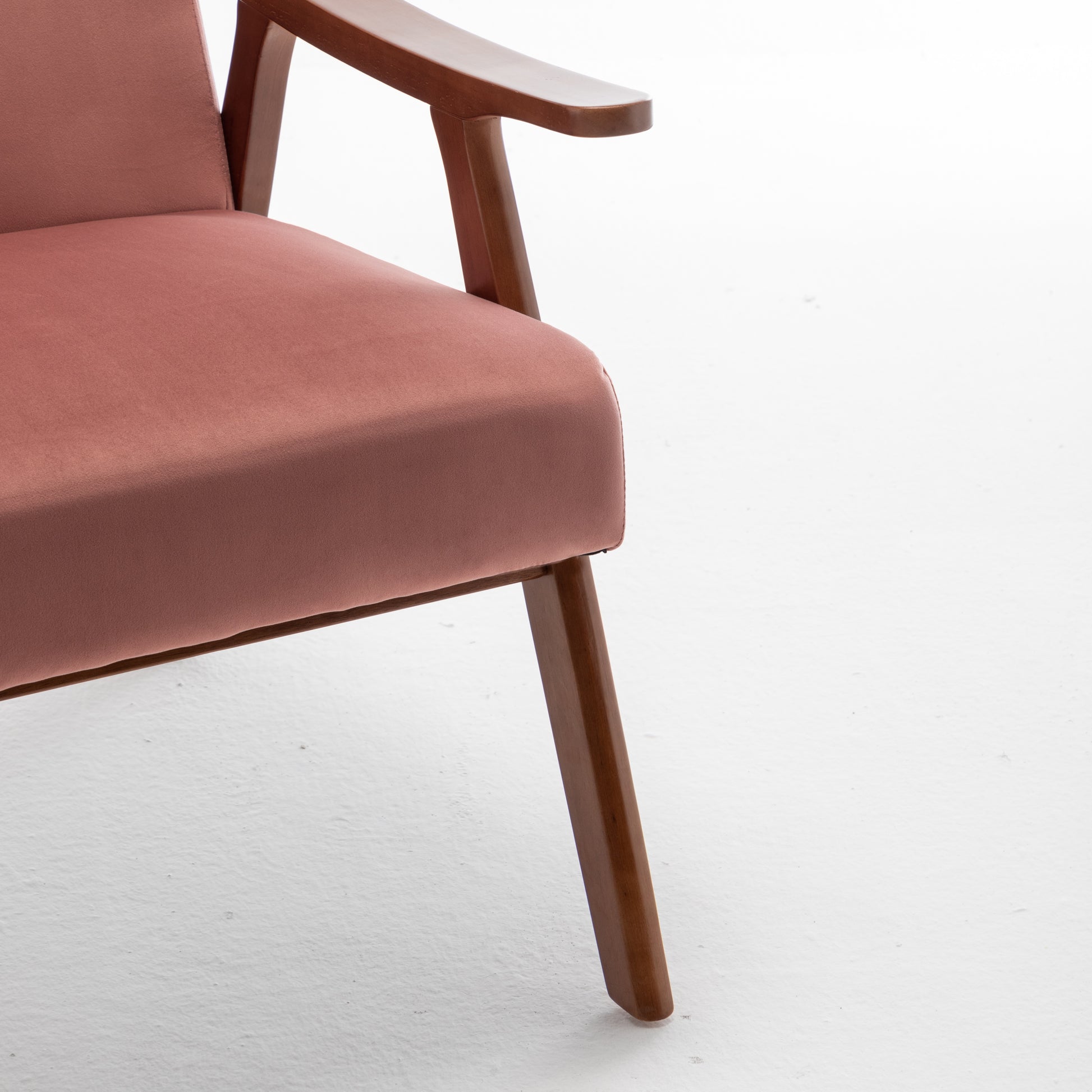 Closeup of dusty rose velvet armchair seat and wooden armrest detail
