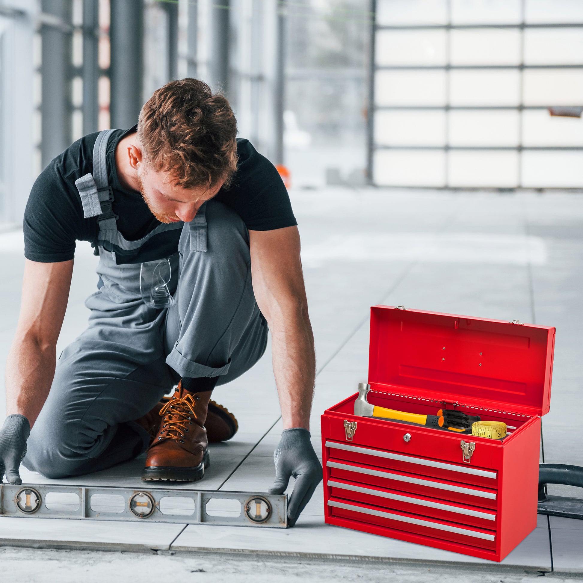 Red metal toolbox with three drawers containing a hammer gloves and tape measure
