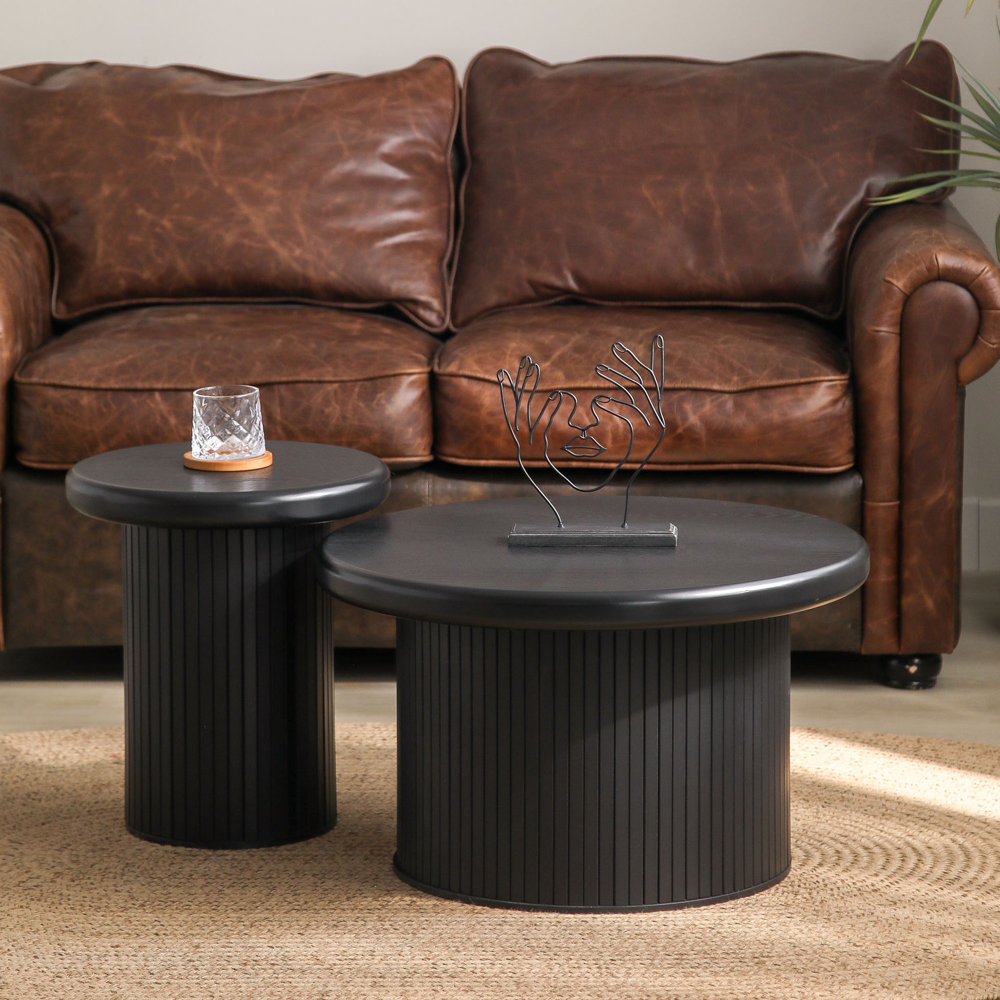 Black fluted round coffee table with modern wire face sculpture centerpiece