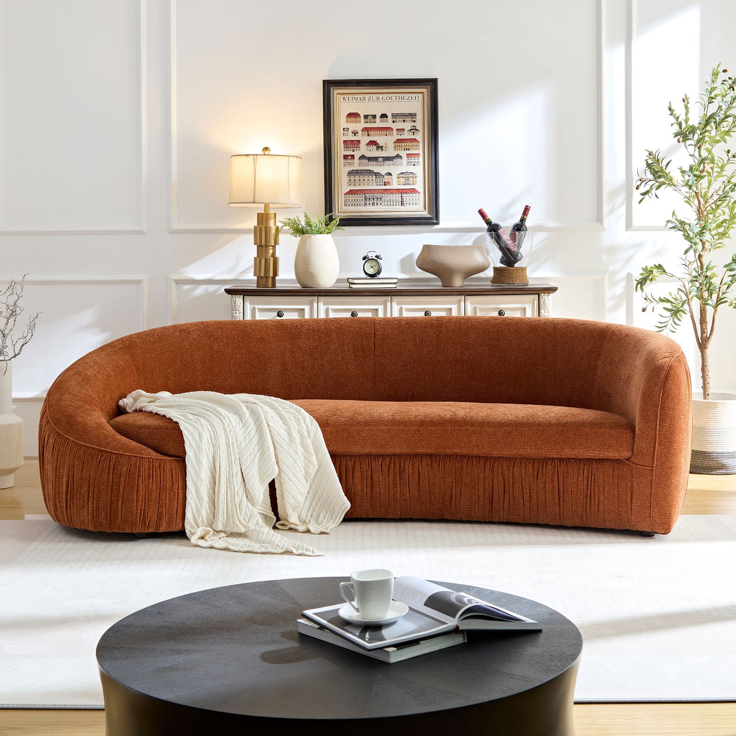 Curved burnt orange sofa with pleated detailing and a cream throw blanket