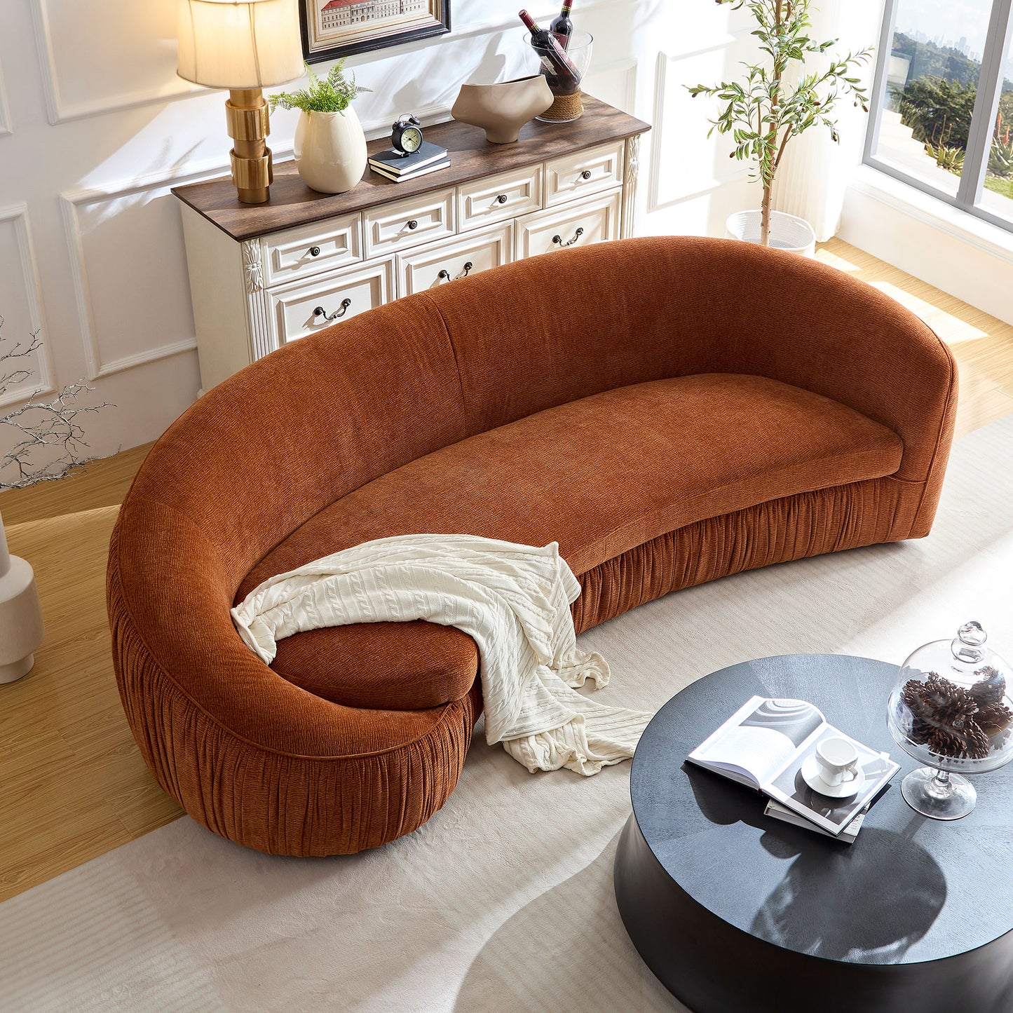 Curved orange boucle sofa with textured pleating on base and a white knit throw
