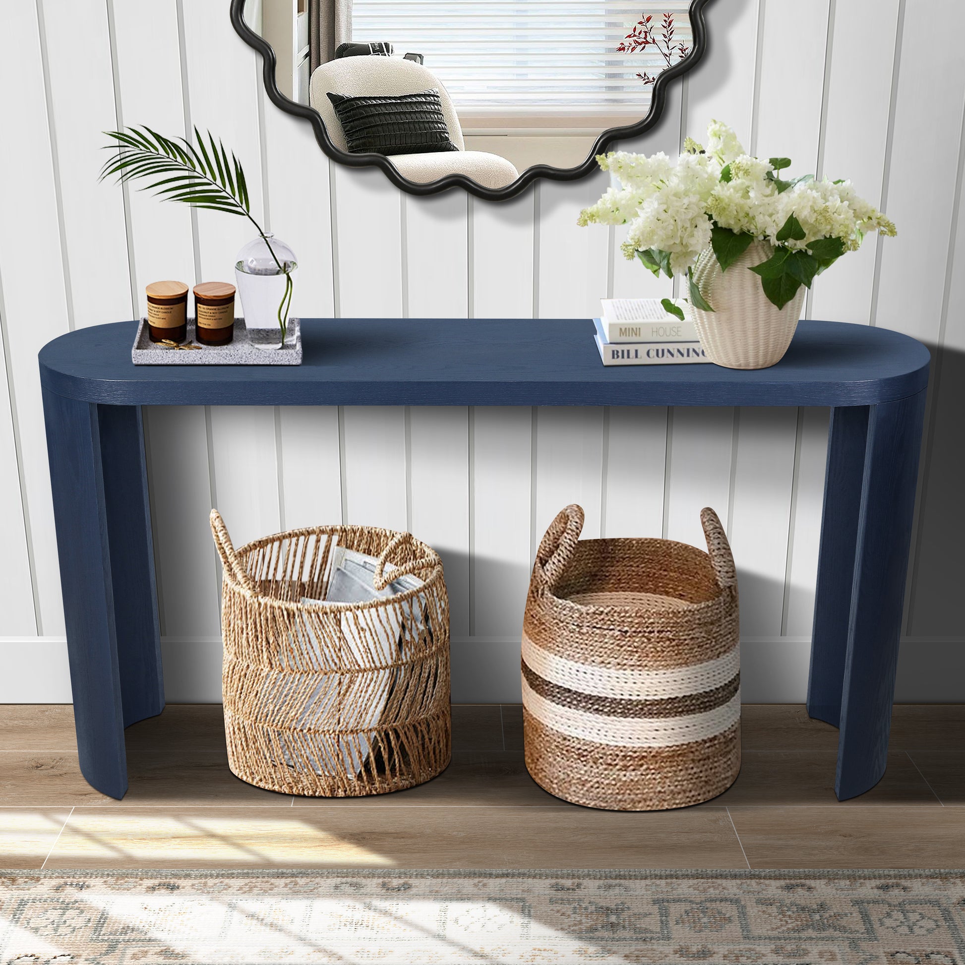 Navy blue oval console table with books and candles on top