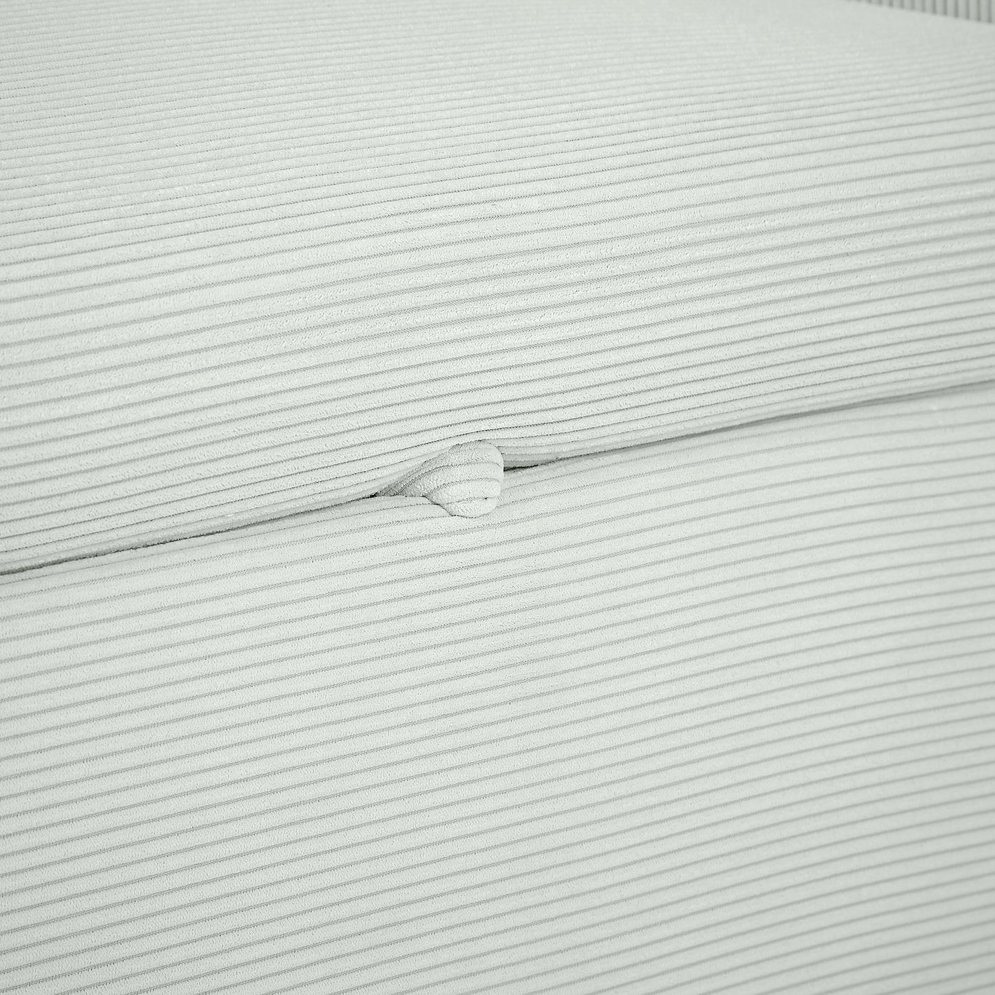 Closeup of light gray corduroy fabric texture with fine horizontal ribs and a raised button detail