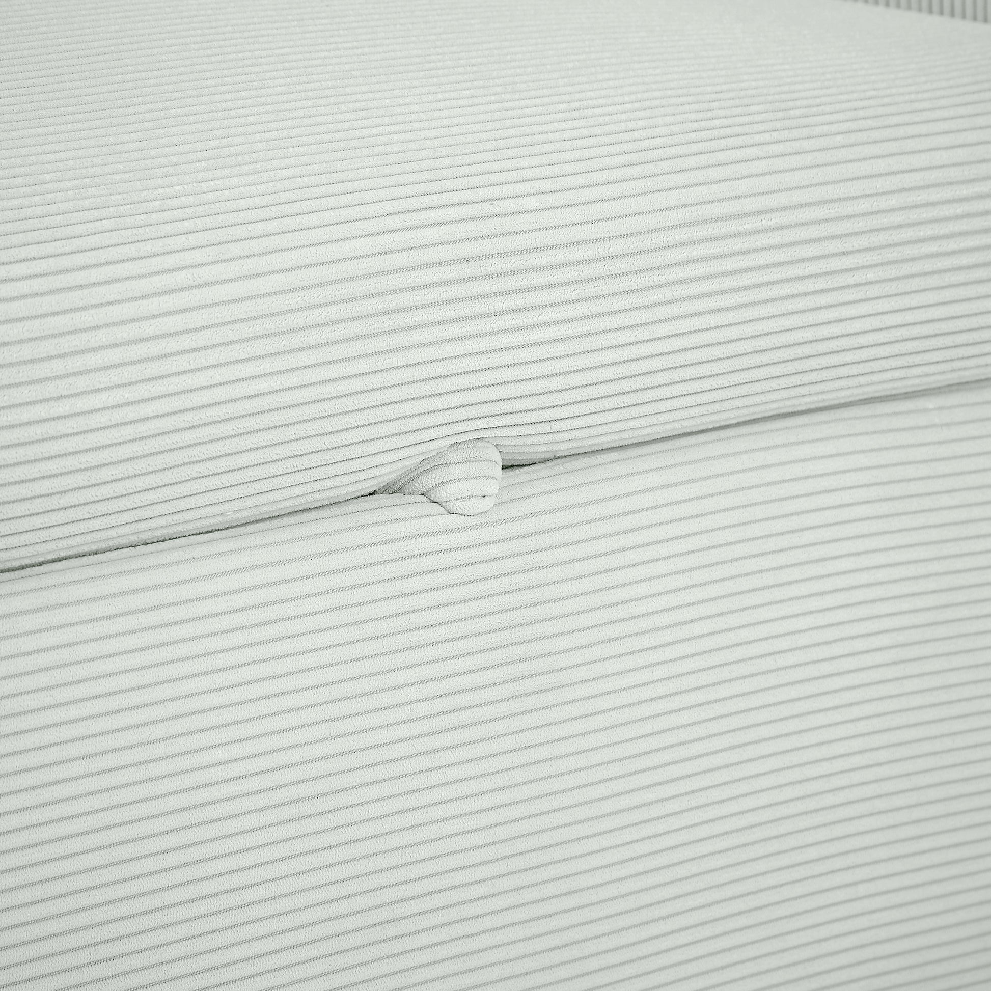 Closeup of light gray corduroy fabric texture with fine horizontal ribs and a raised button detail