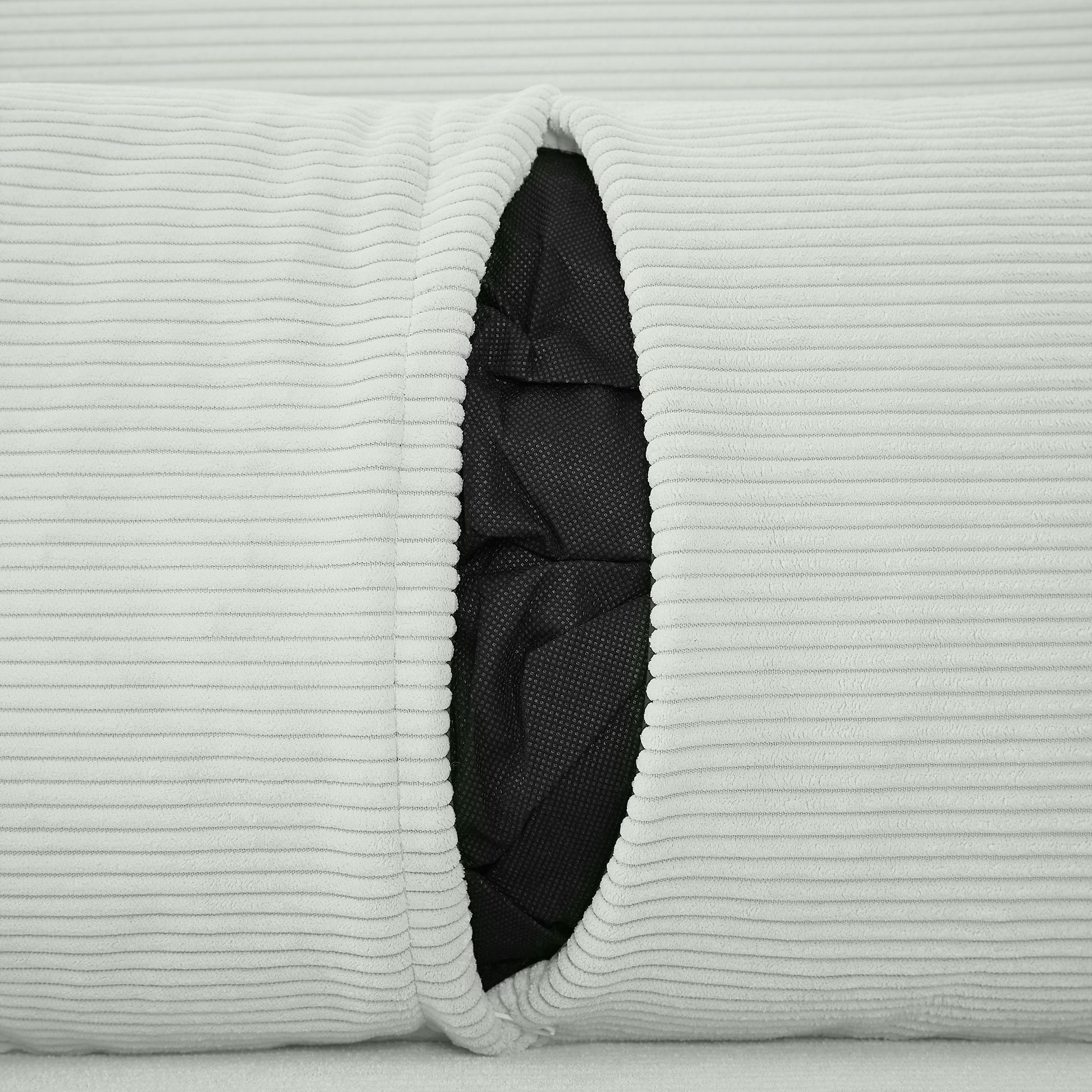 Closeup of light grey corduroy fabric with a visible black interior liner