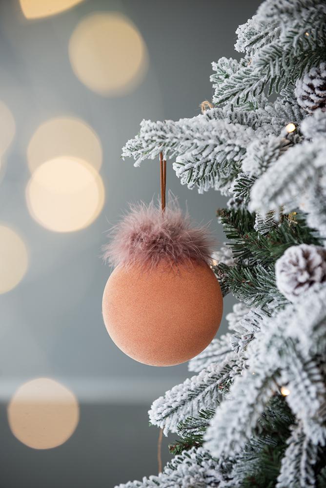 Flocked Christmas tree branch with soft peach bauble adorned with fluffy pink trim
