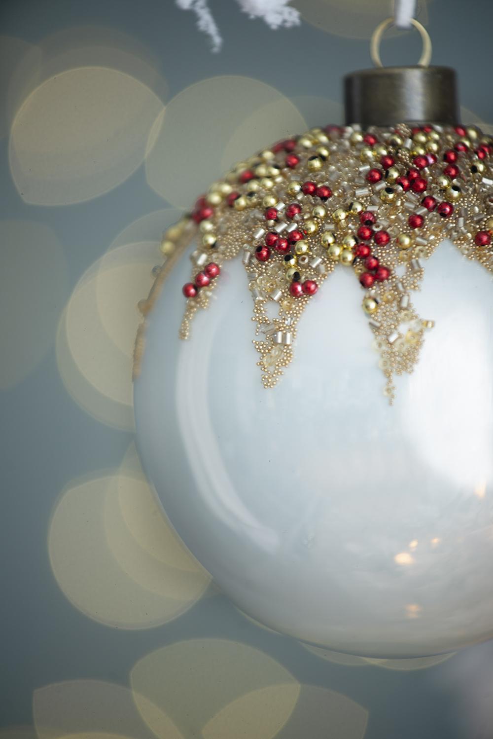 White glass Christmas ornament with red and gold bead embellishments