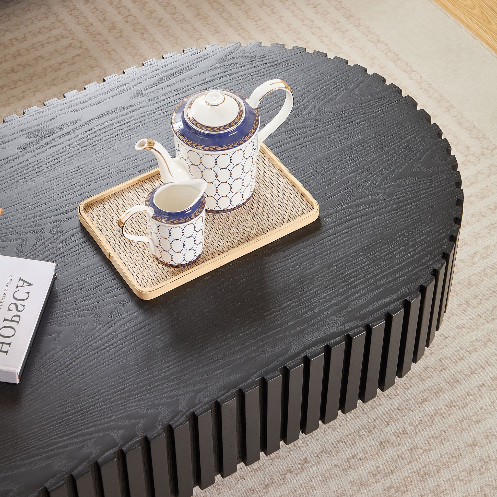 Black oval coffee table with fluted sides and a book