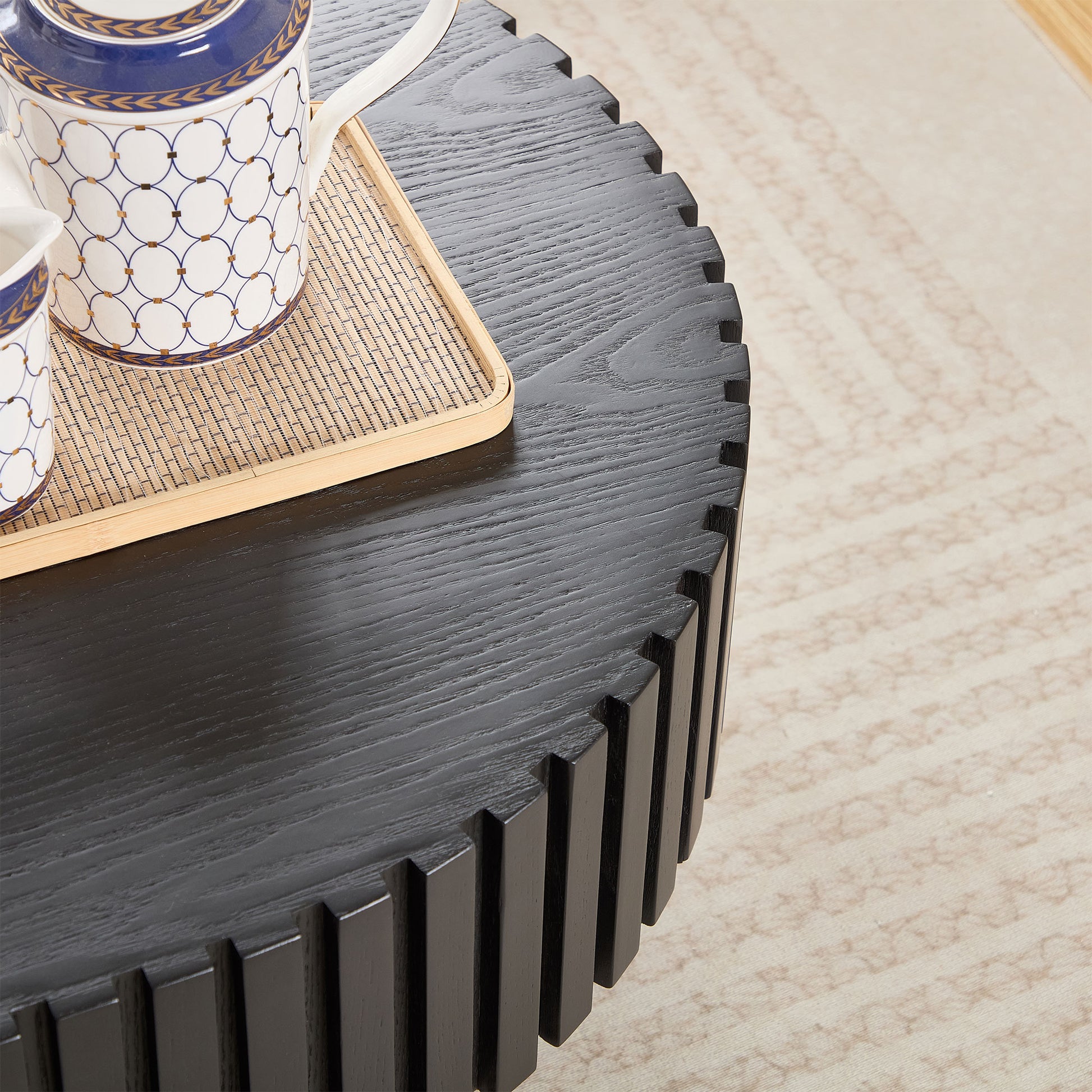 Black textured round coffee table with ornate tea set on bamboo tray