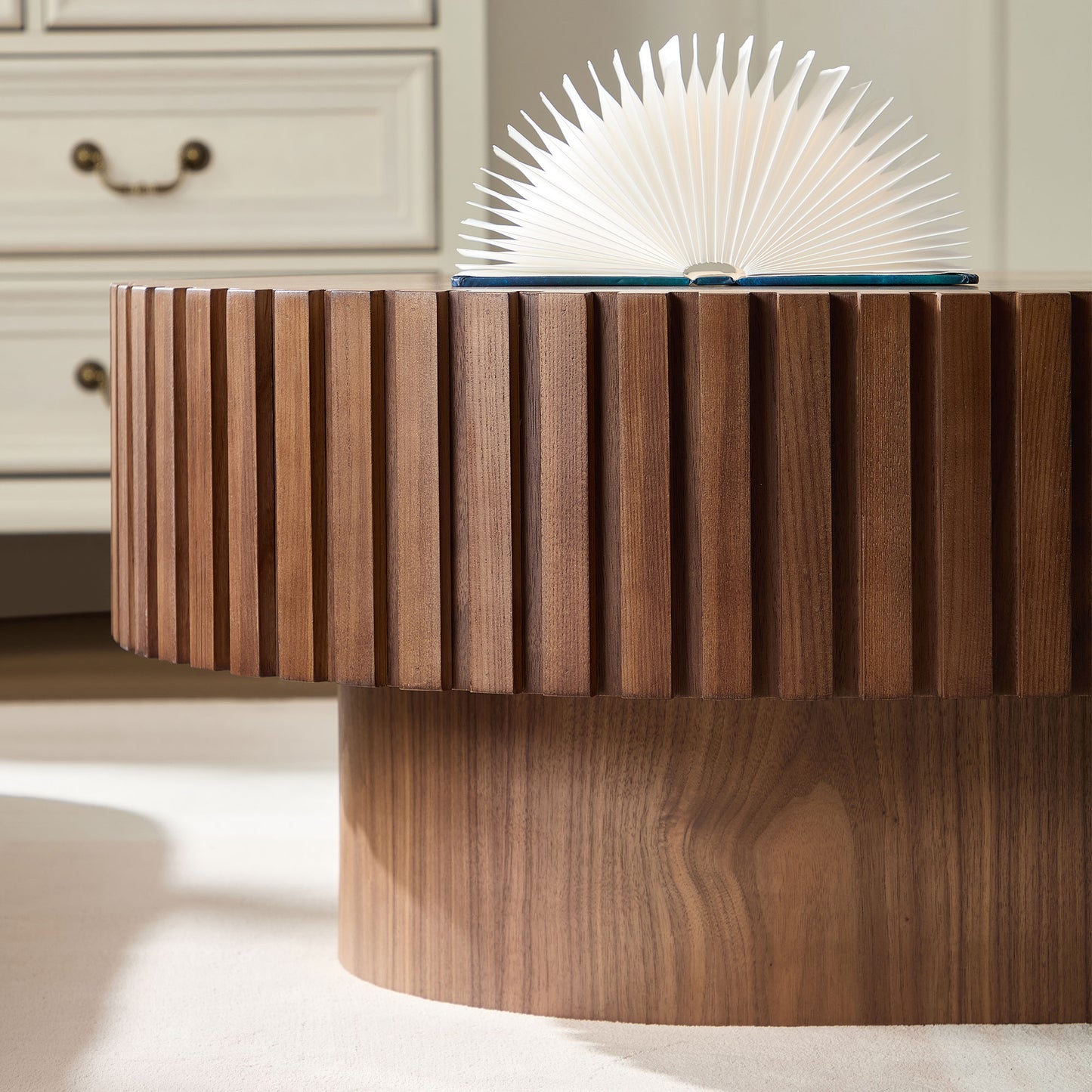 Round fluted walnut coffee table with a book open on top