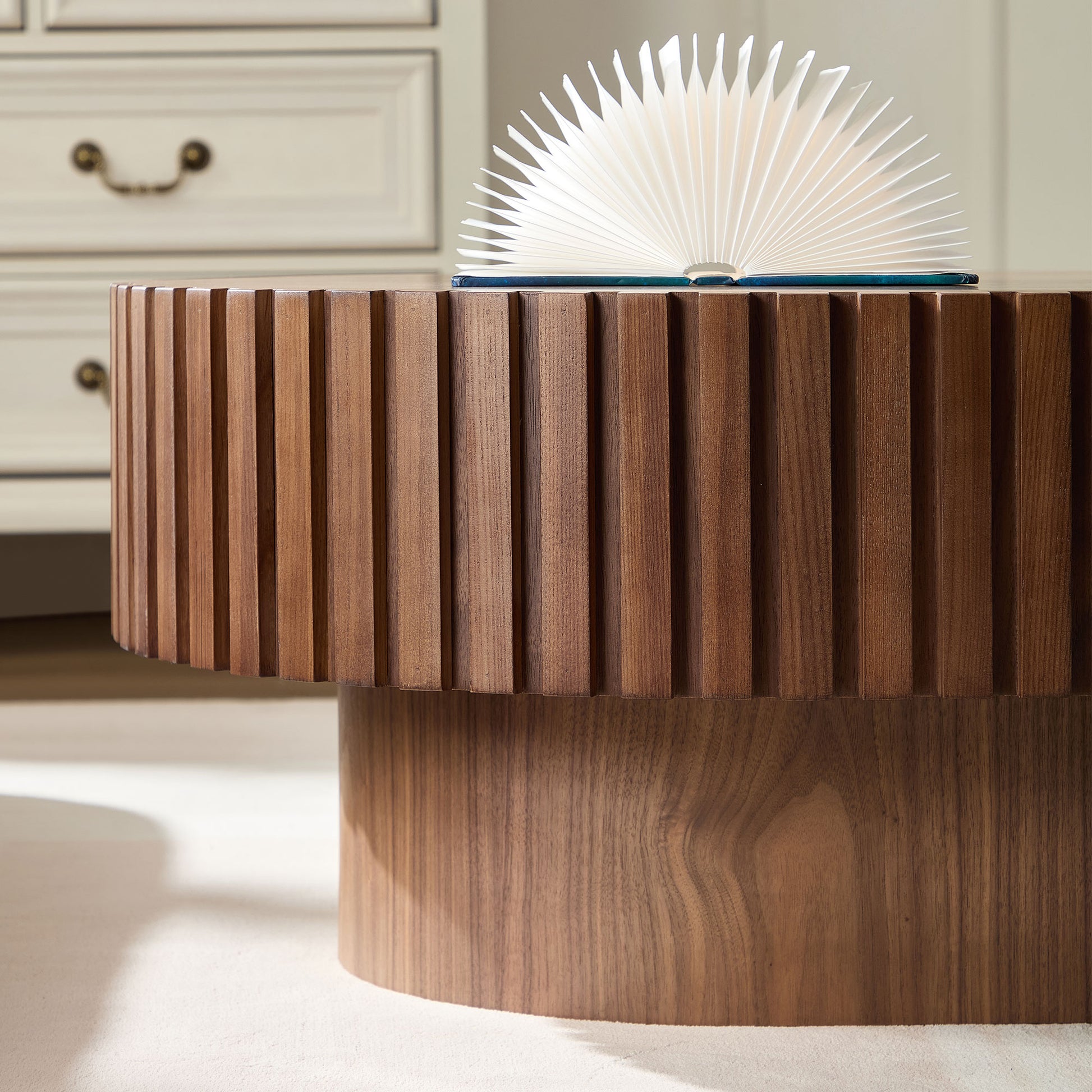 Round fluted walnut coffee table with a book open on top