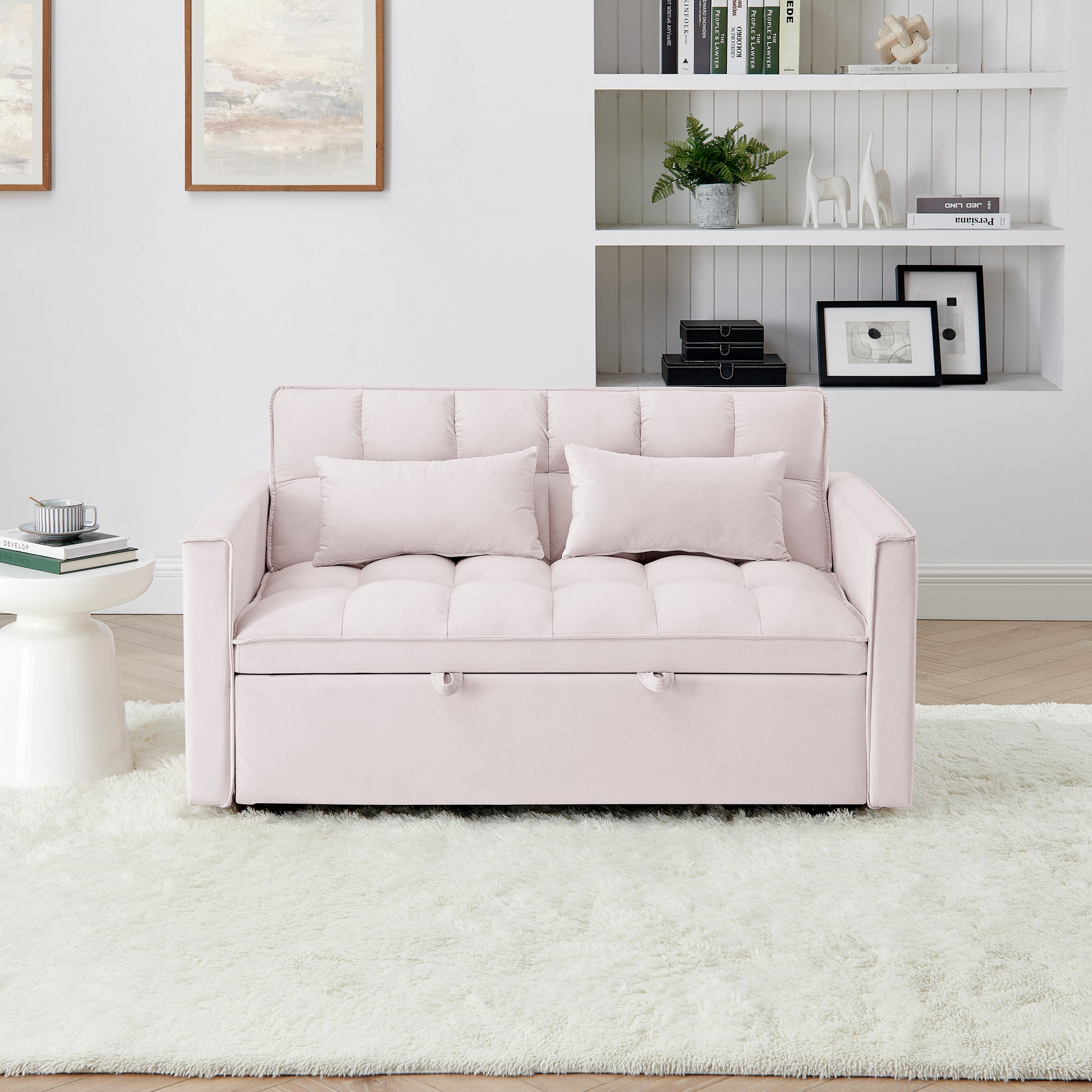 A plush pink velvet sofa bed with tufted cushions and two matching throw pillows