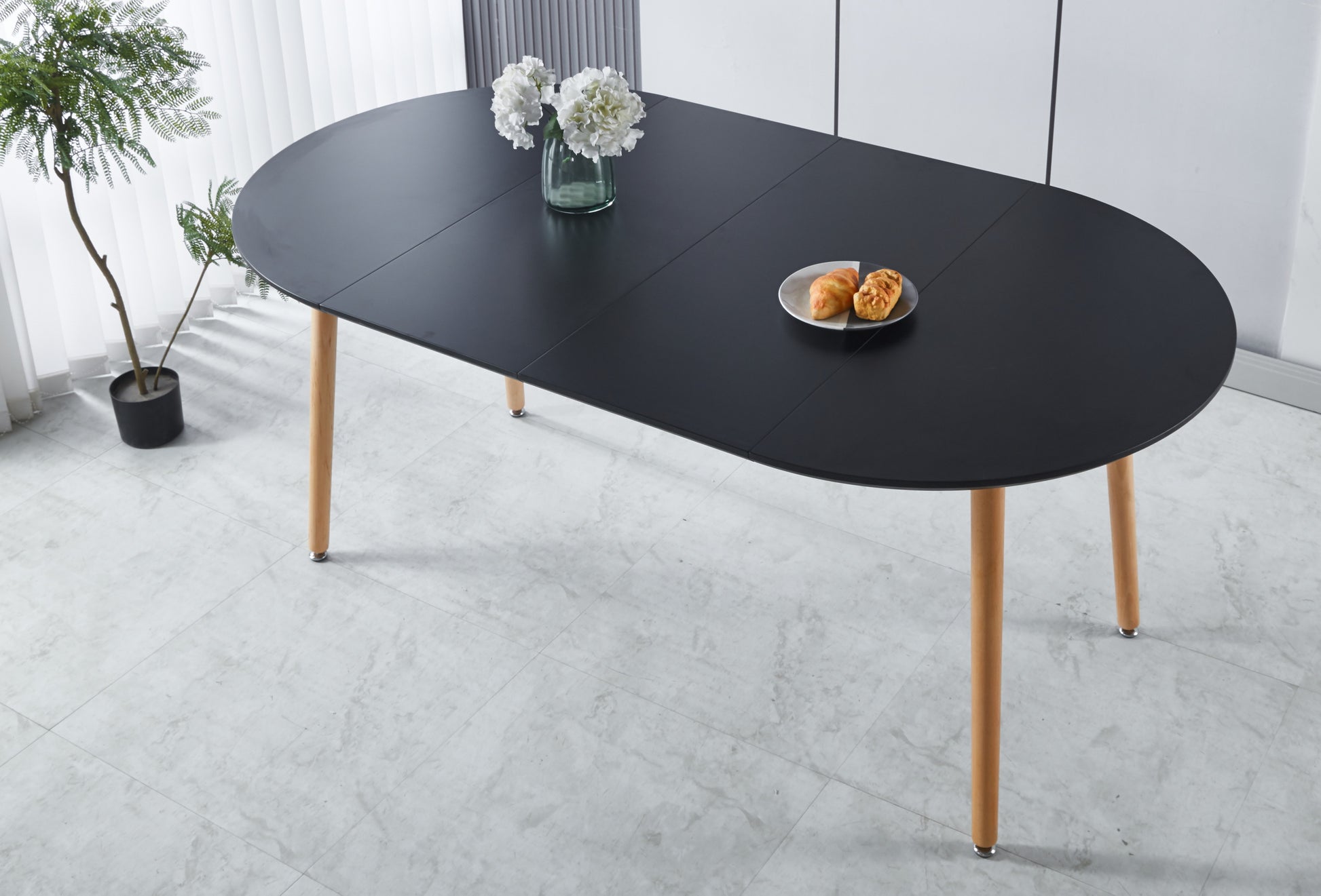 Modern black oval dining table with natural wood legs ideal for small spaces