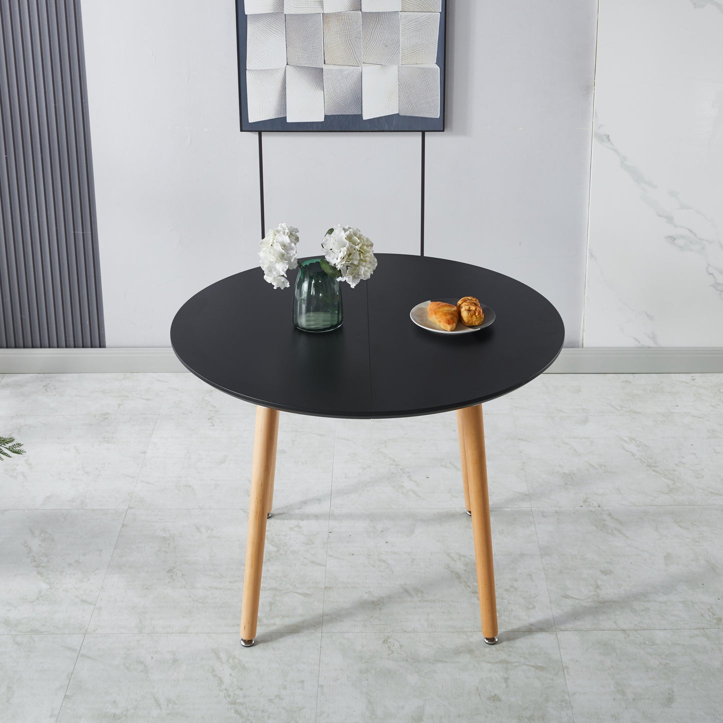 Black round dining table with light wood legs and two pastries on a plate
