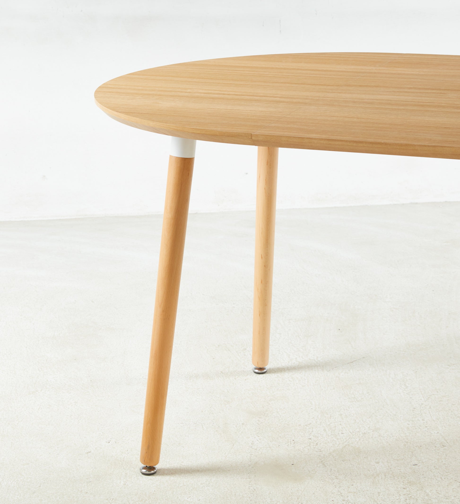 Round oak dining table with tapered wooden legs and white accents