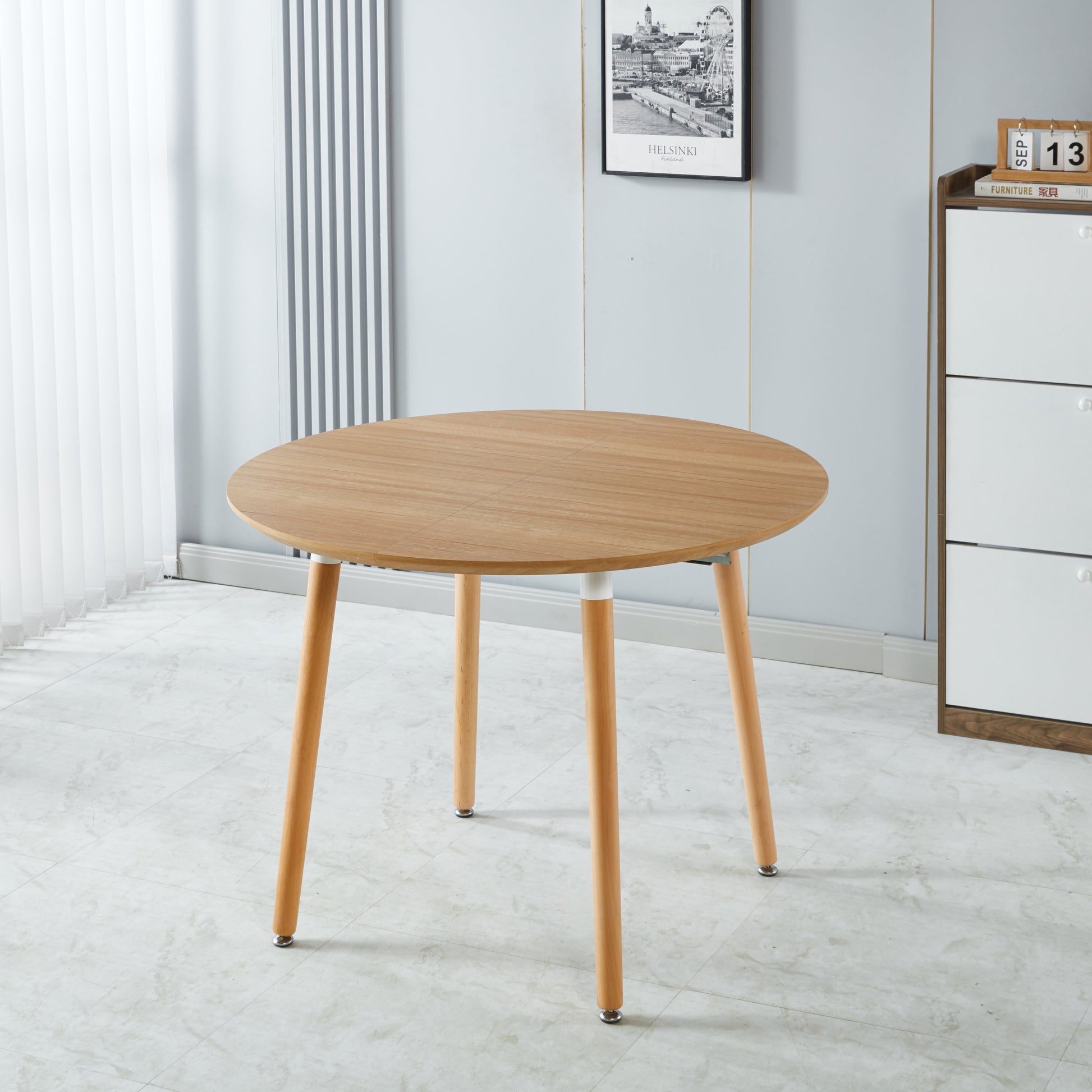 Round light wood dining table with natural grain four tapered legs perfect for compact spaces