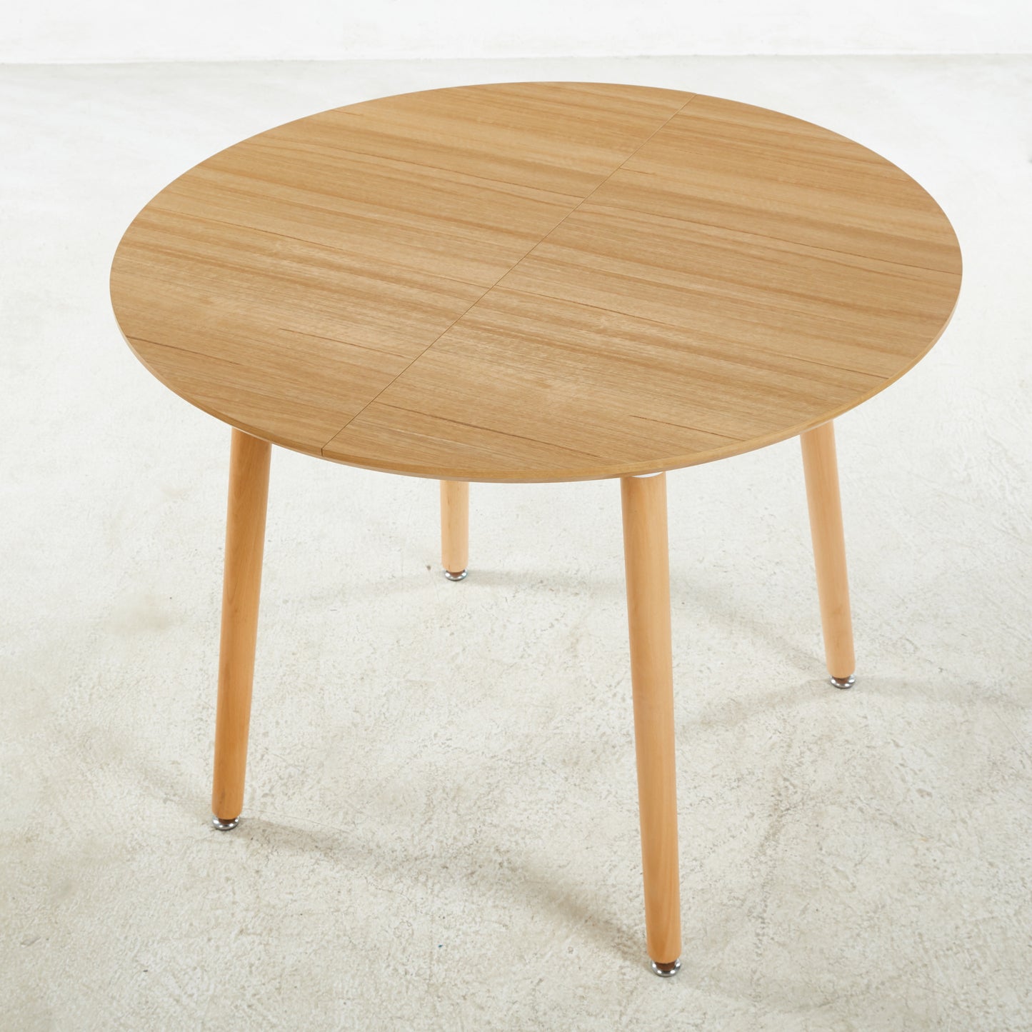 Round oak dining table with four tapered wooden legs and brushed metal feet