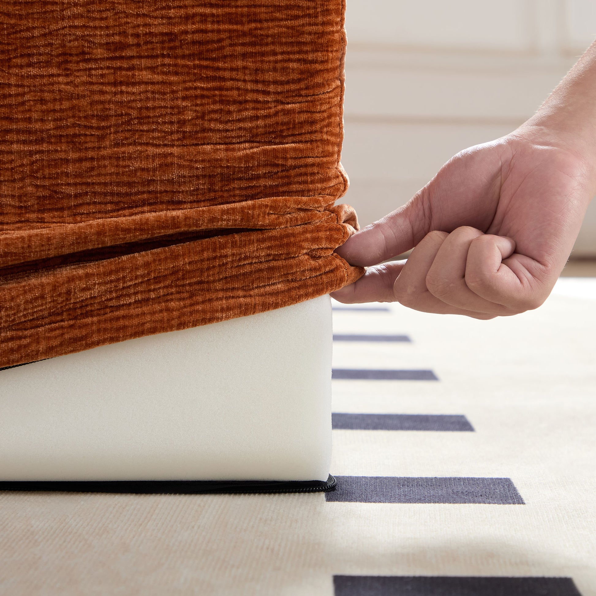 Brown corduroy sofa slipcover being fitted onto white foam cushion
