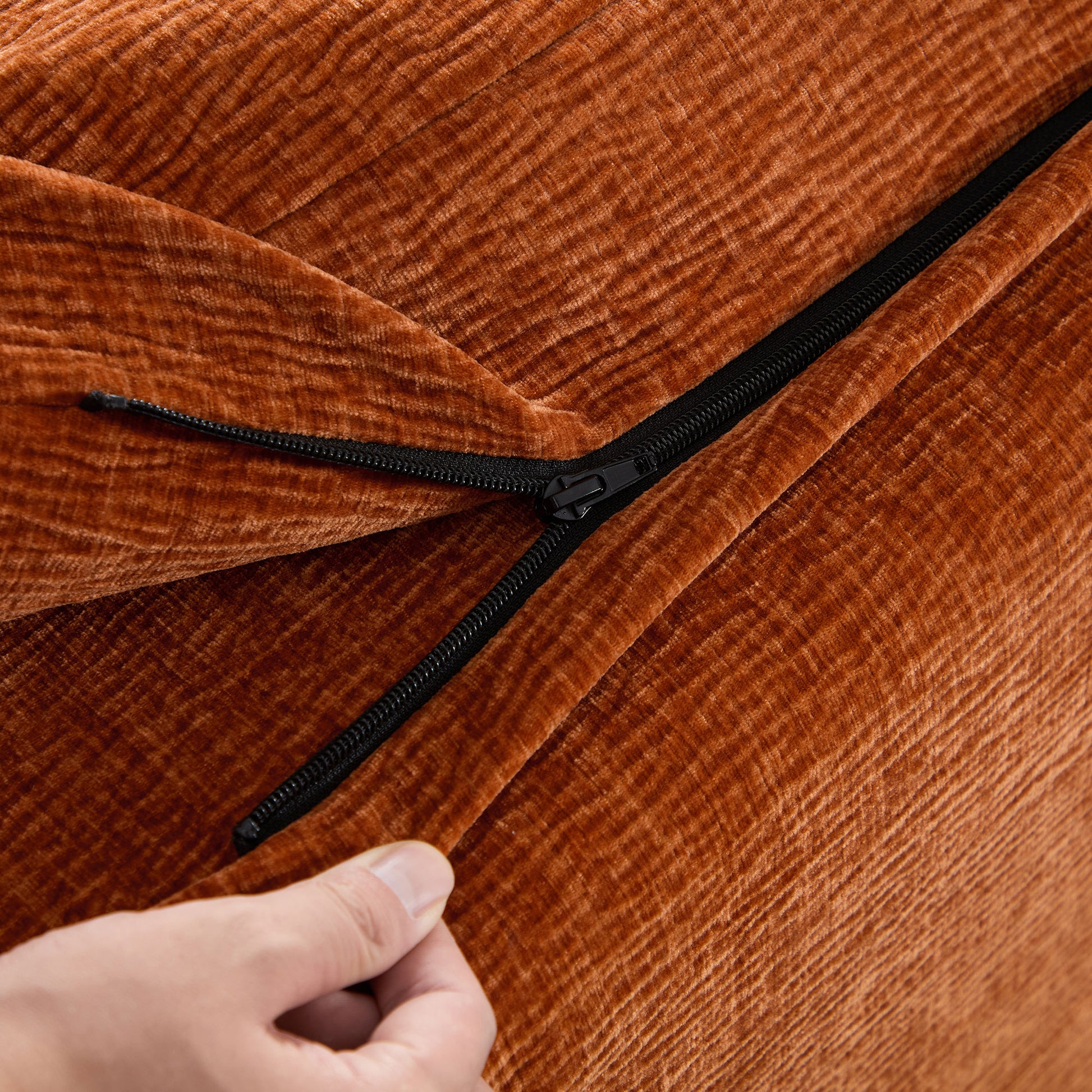 Closeup of an orange corduroy fabric with a visible black zipper showcasing texture