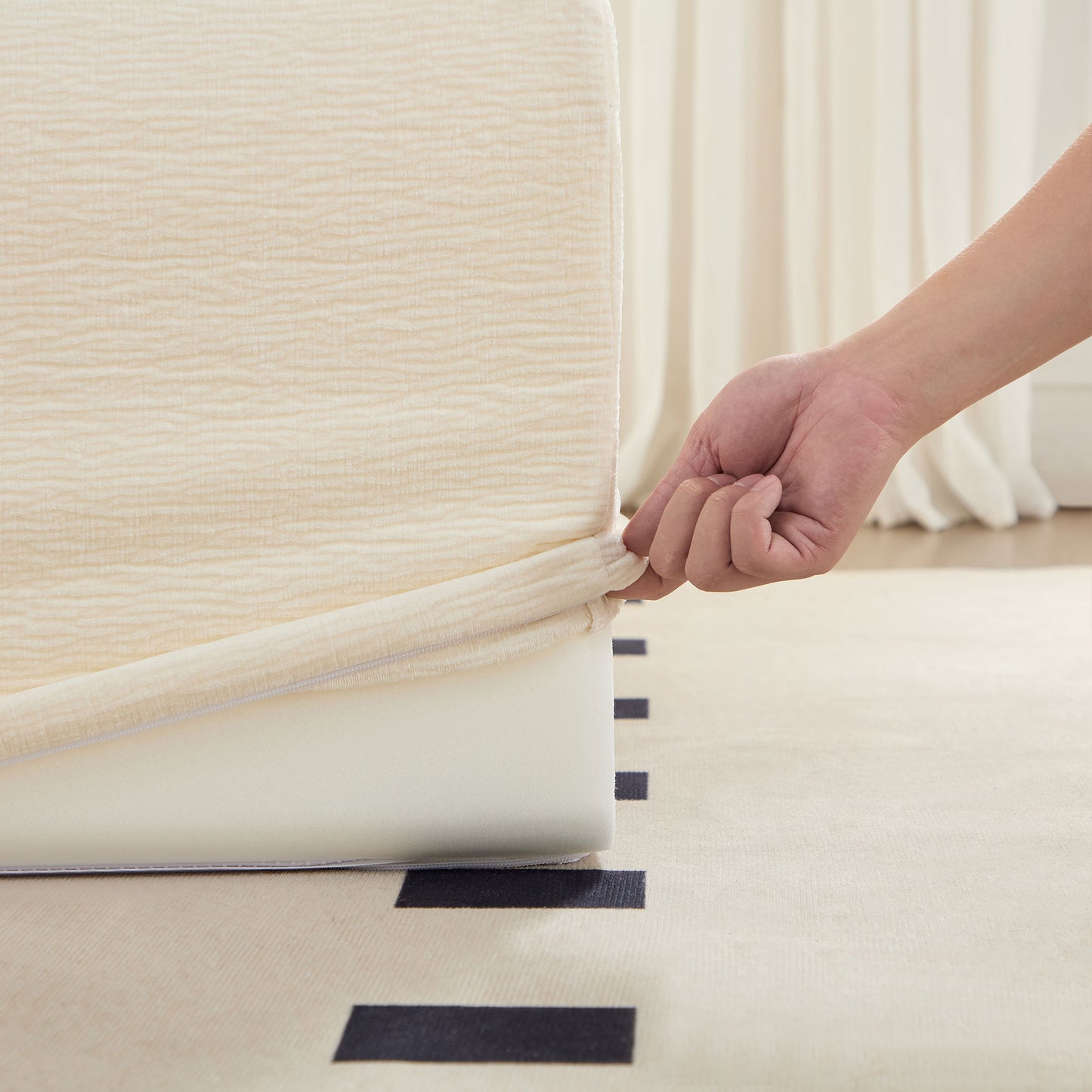 Cream textured fitted bed sheet being stretched onto a mattress