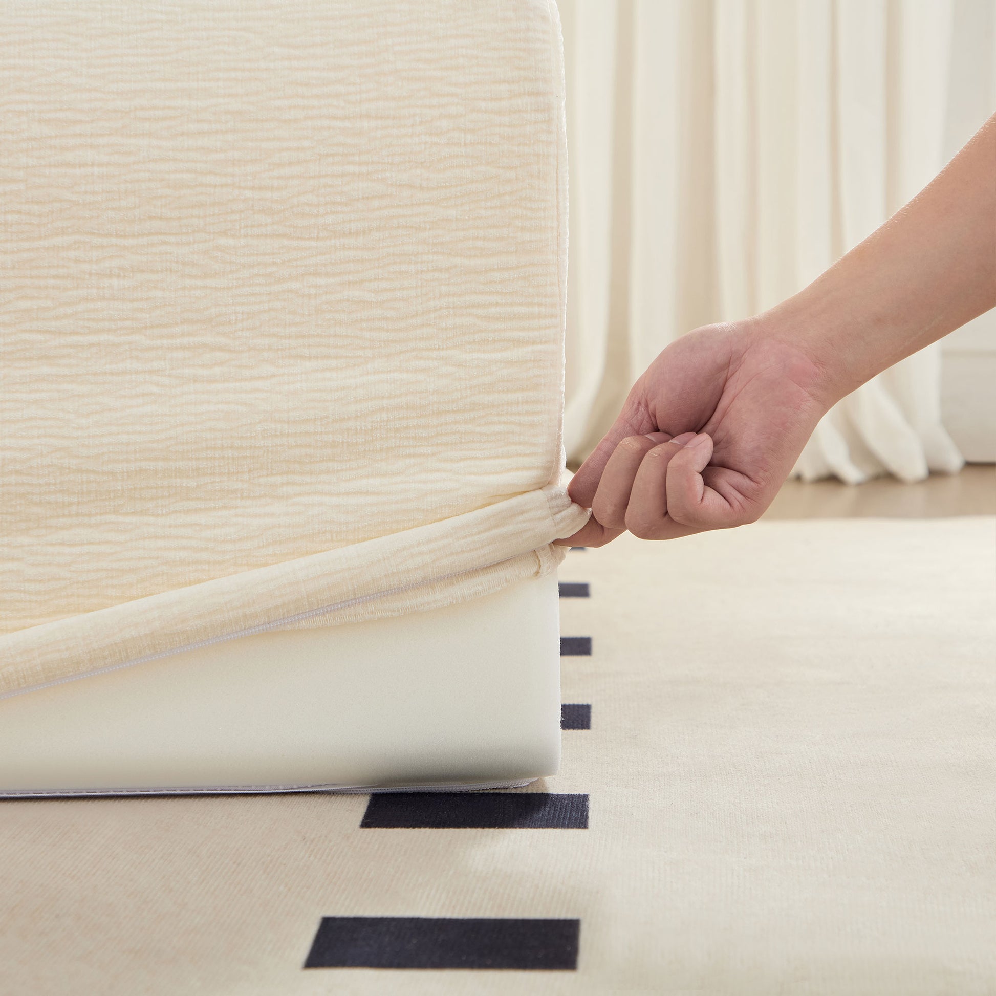 Cream textured fitted bed sheet being stretched onto a mattress