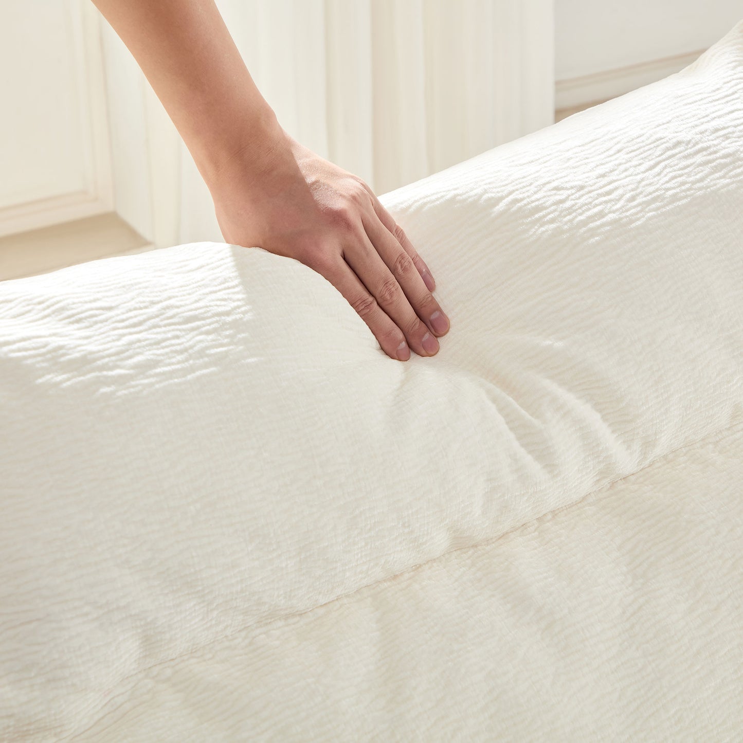 Closeup of hand touching a soft textured white duvet cover