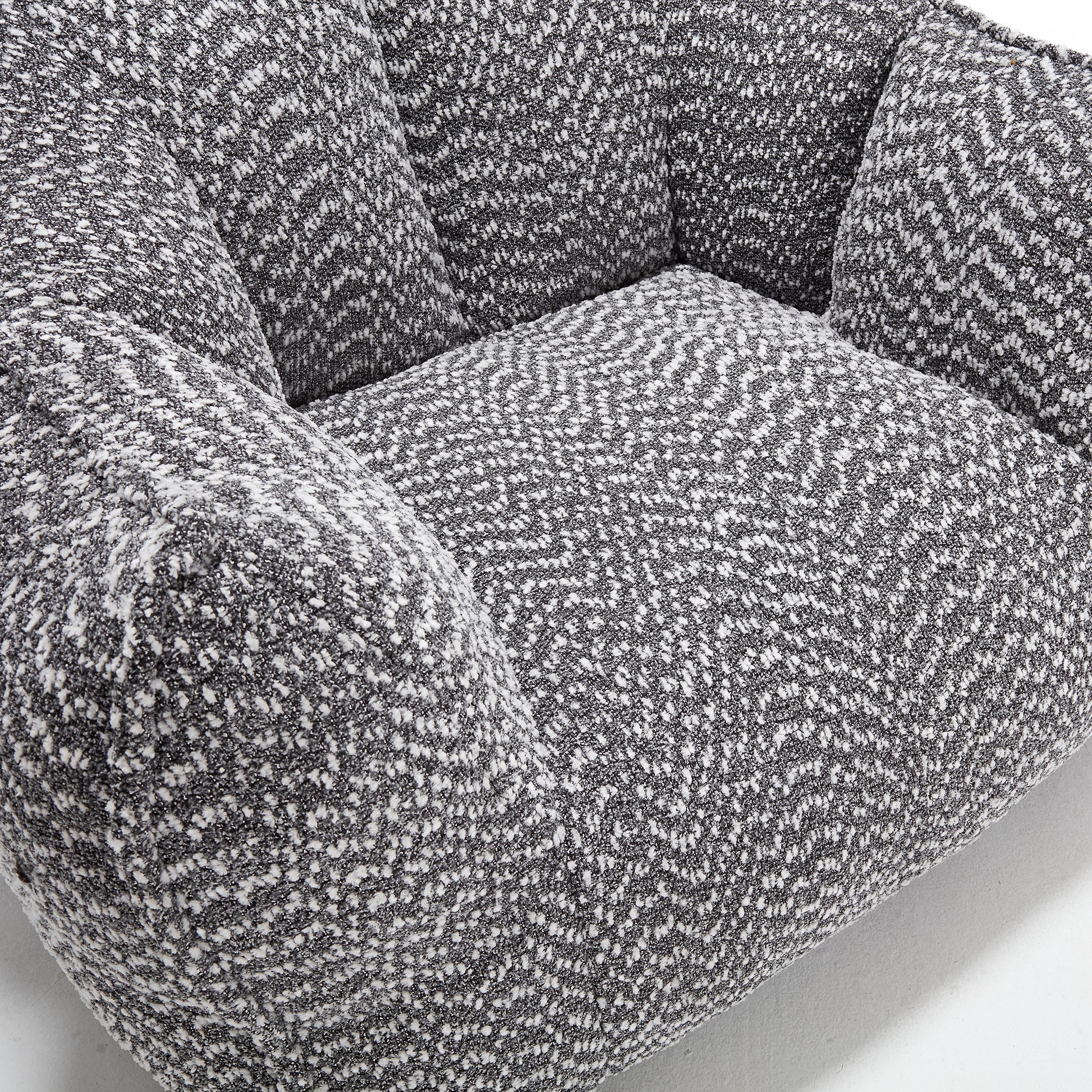Closeup of a grey and white textured fabric armchair cushion with a boucl weave