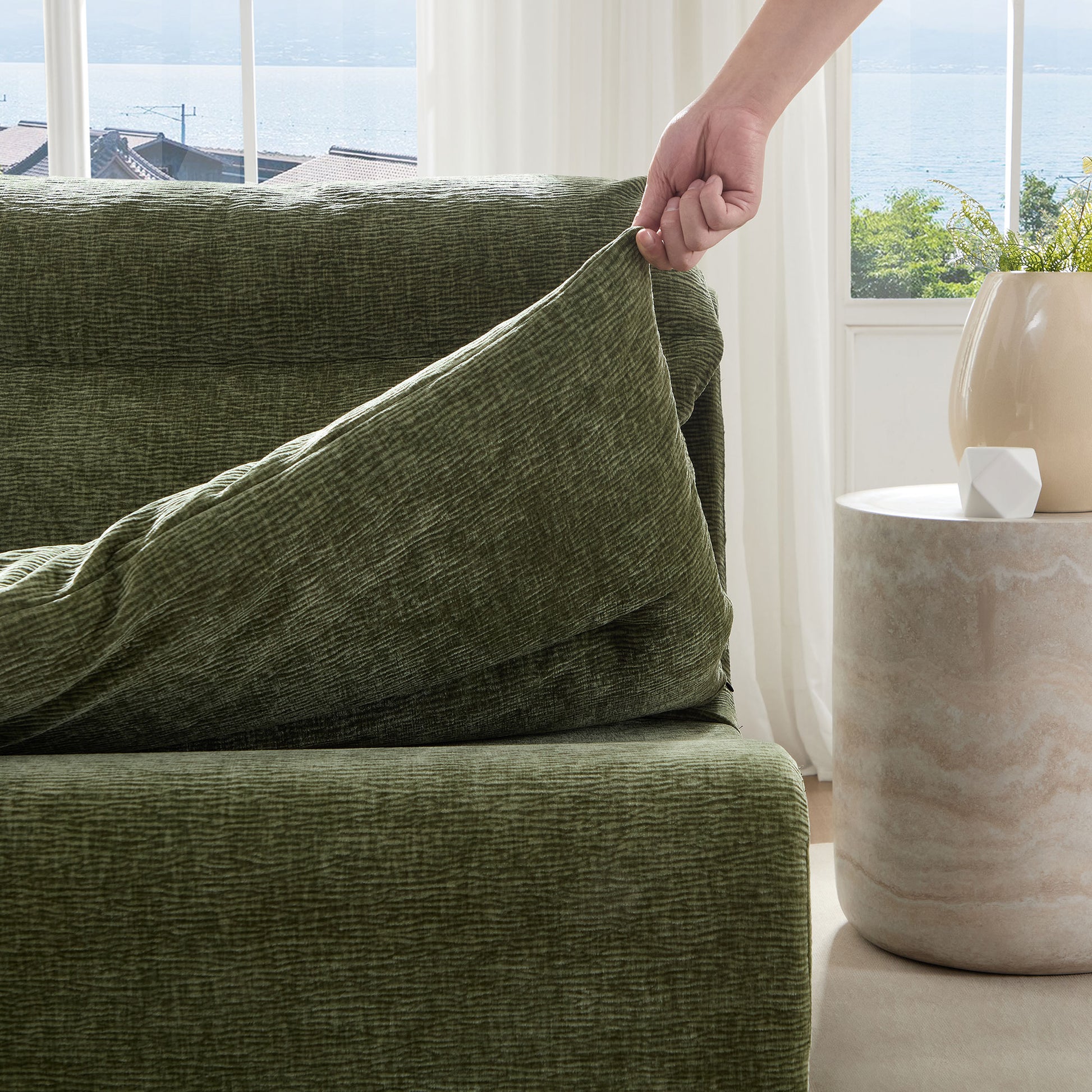Green textured sofa slipcover being applied offering a cozy and protective furniture upgrade