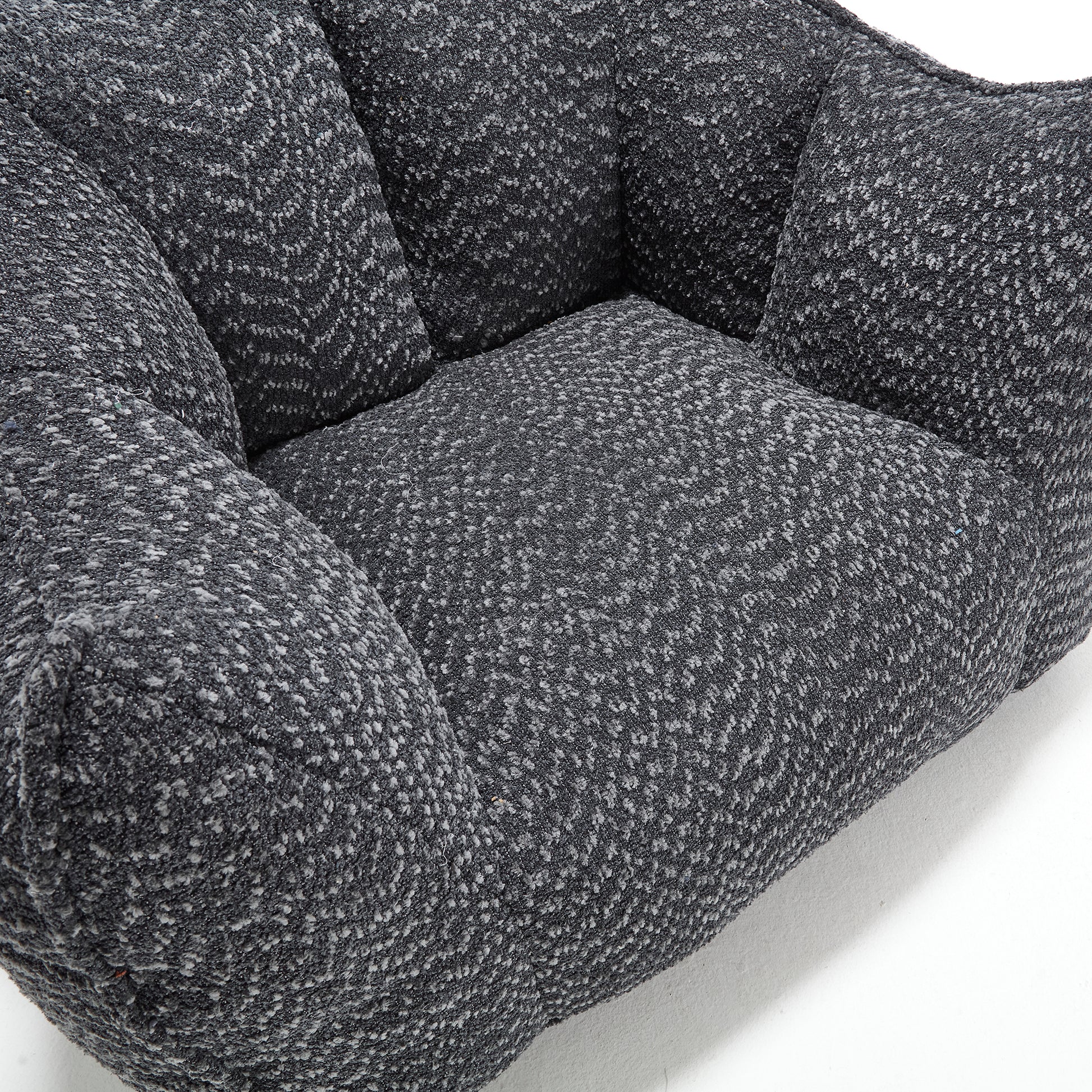 Closeup of a textured dark grey armchair with plush cushioning perfect for modern living rooms
