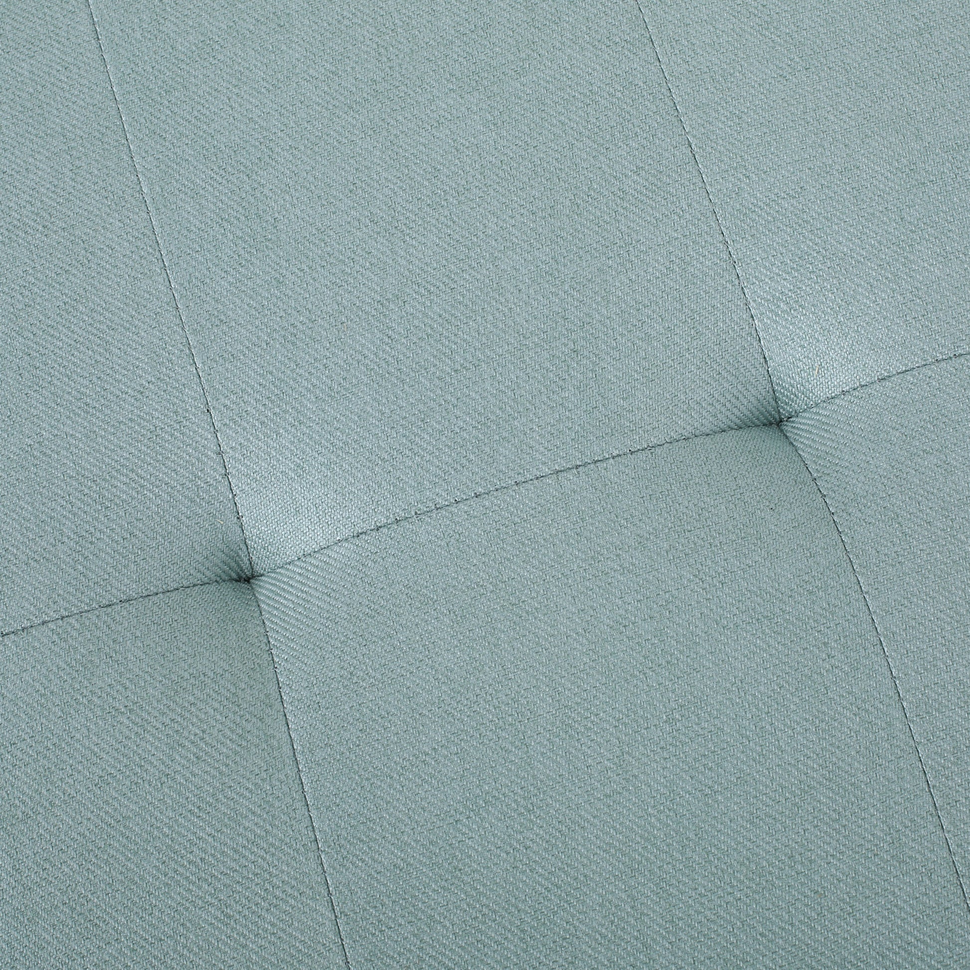 Closeup of light teal upholstered fabric with diamond tufting detail