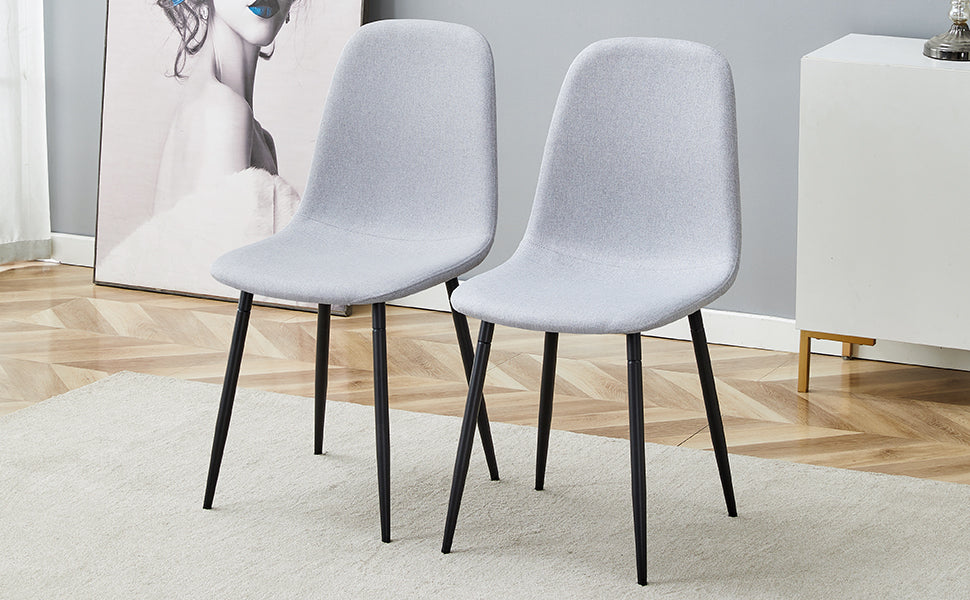 Two grey fabric dining chairs with black metal legs sit on a rug