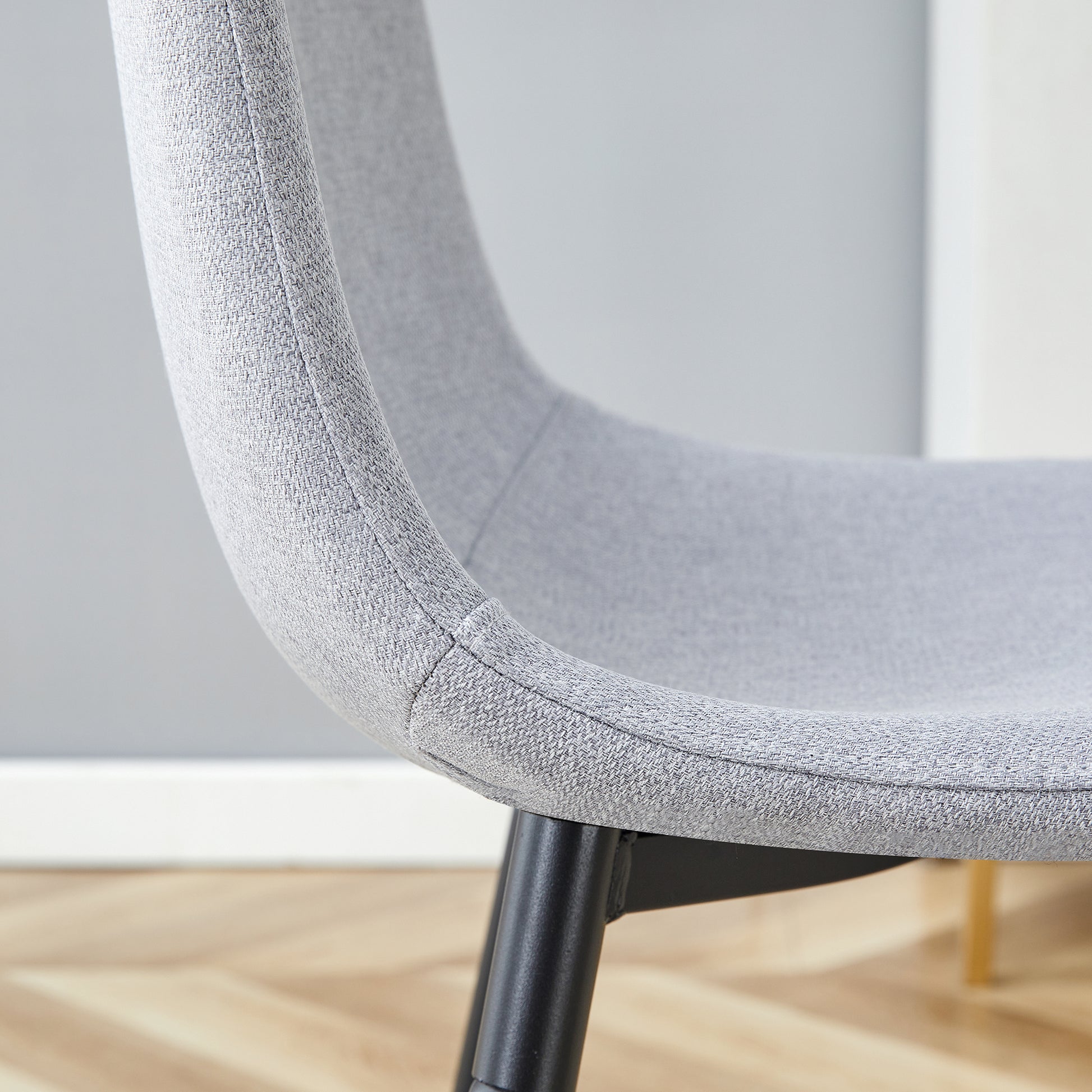Closeup of a grey fabric dining chair with black metal legs