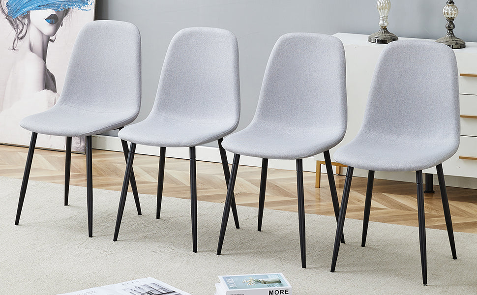 Four light grey upholstered dining chairs with black tapered legs