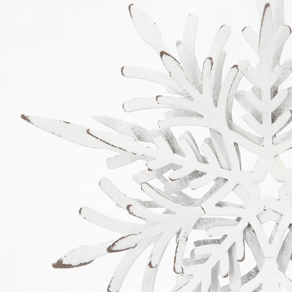 Distressed white metal snowflake decoration with intricate layered arms and rustic charm