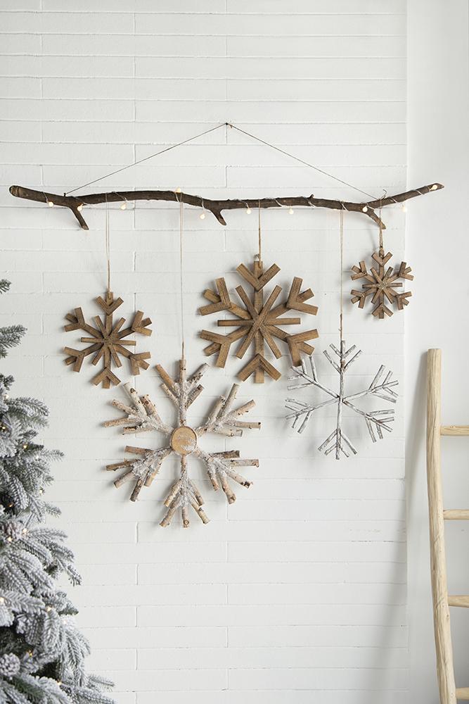 Rustic wood snowflake ornaments hanging from a branch with fairy lights