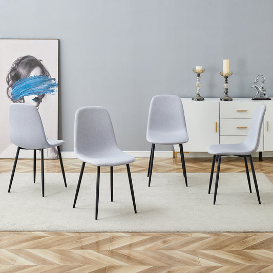 Four light grey upholstered dining chairs with black tapered legs on a cream rug