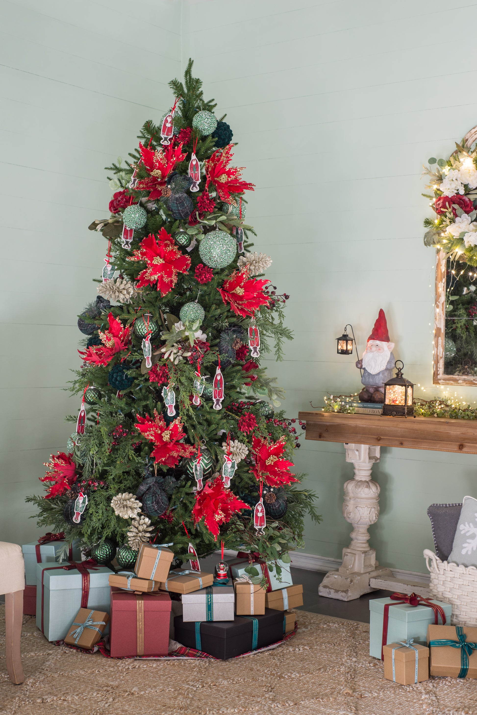 Festively decorated Christmas tree with red poinsettias glitter ornaments and gnome tags