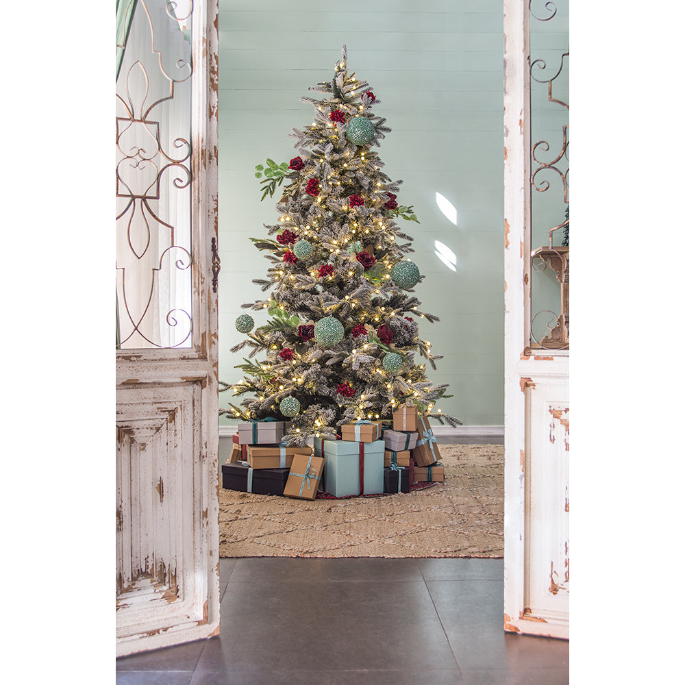 Flocked artificial Christmas tree with red roses green ornaments and warm LED lights