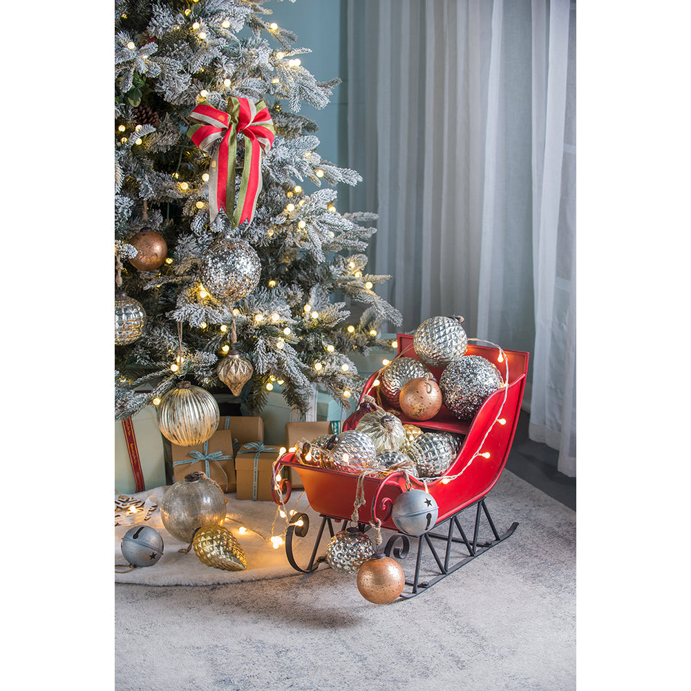 Flocked Christmas tree adorned with silver ornaments and a festive red green and white striped bow