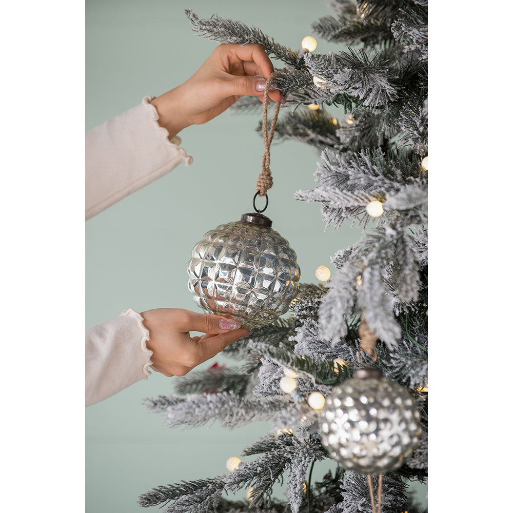 Silver textured glass Christmas bauble with rope hanger being placed on tree