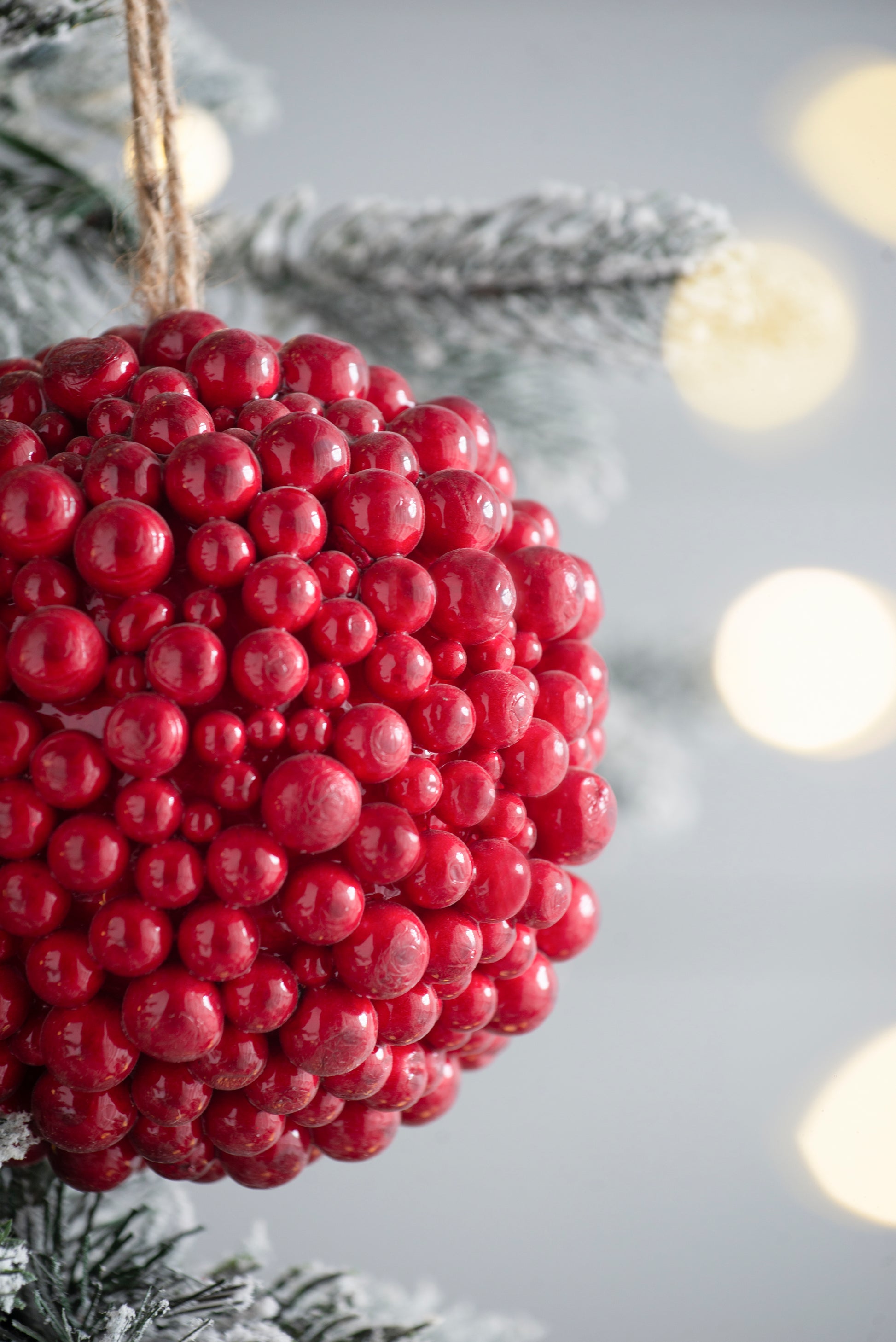 Textured red berry Christmas ornament on a flocked tree branch