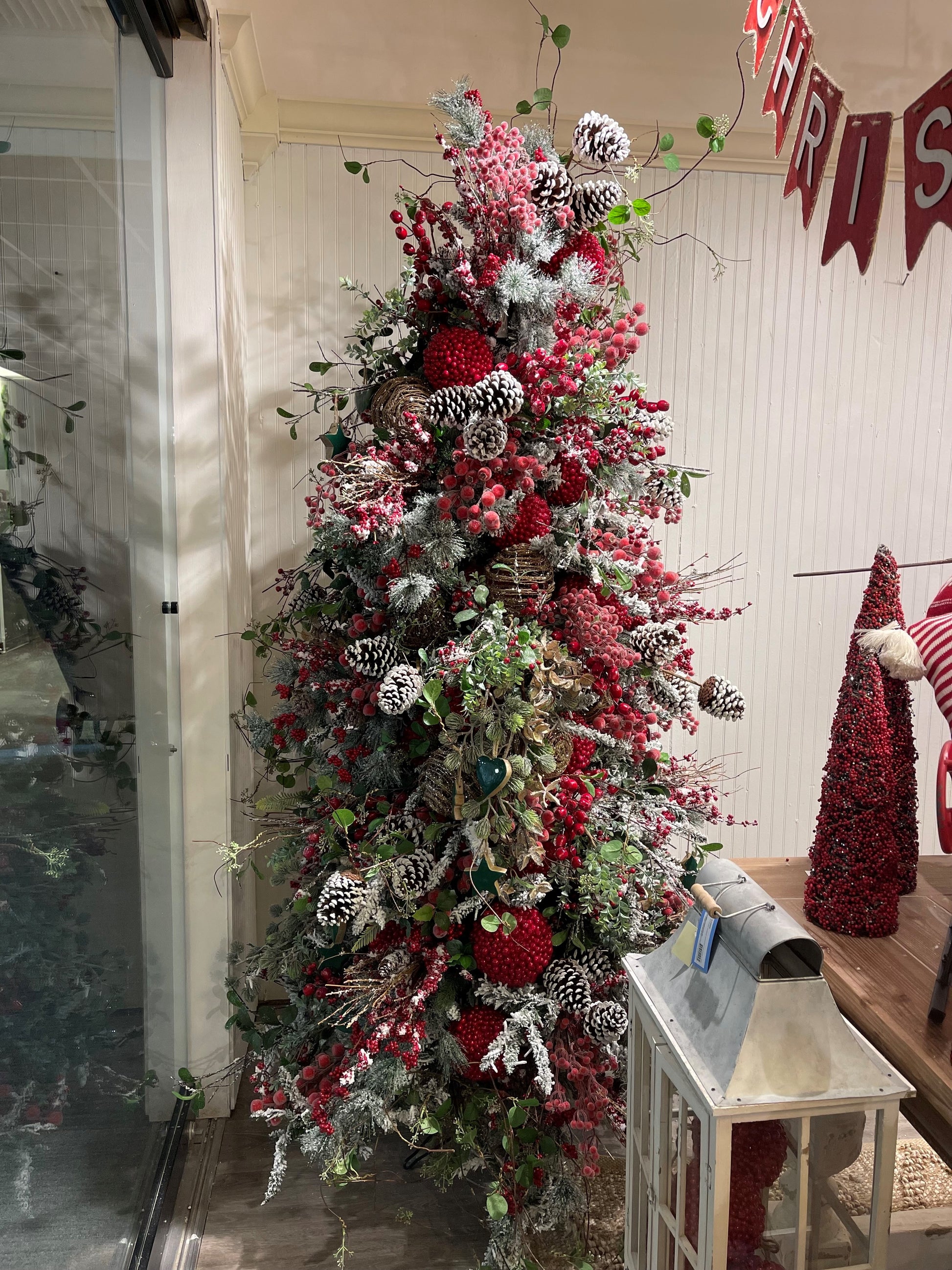 Frosted artificial Christmas tree adorned with red berries pinecones and flocked branches