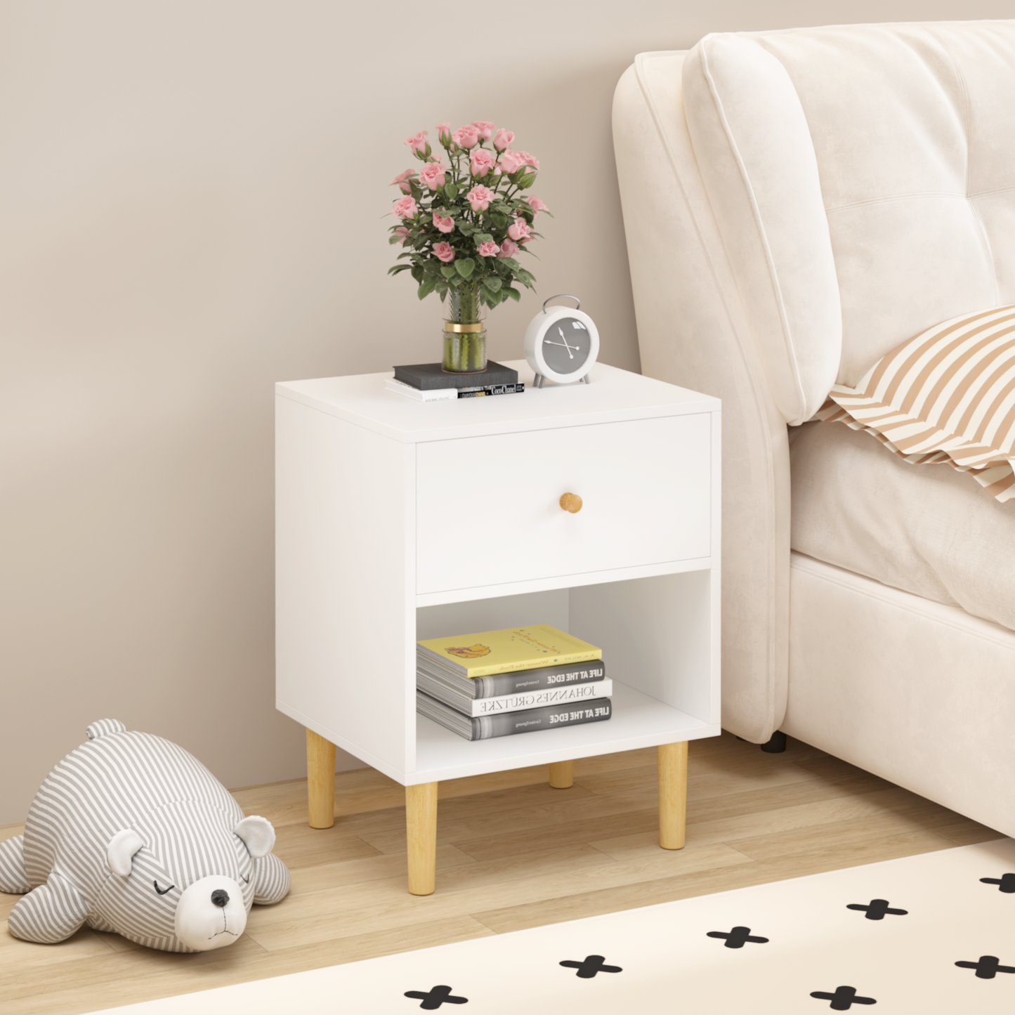 White nightstand with wooden legs open shelf and drawer holding books and decor