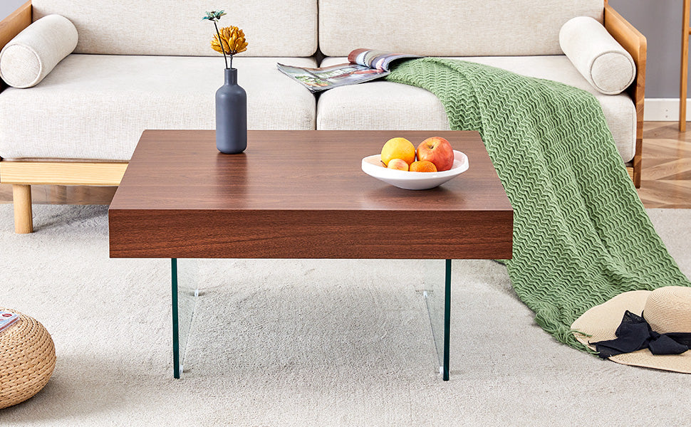 Modern square coffee table with dark wood top and clear glass legs elegantly placed in a living room
