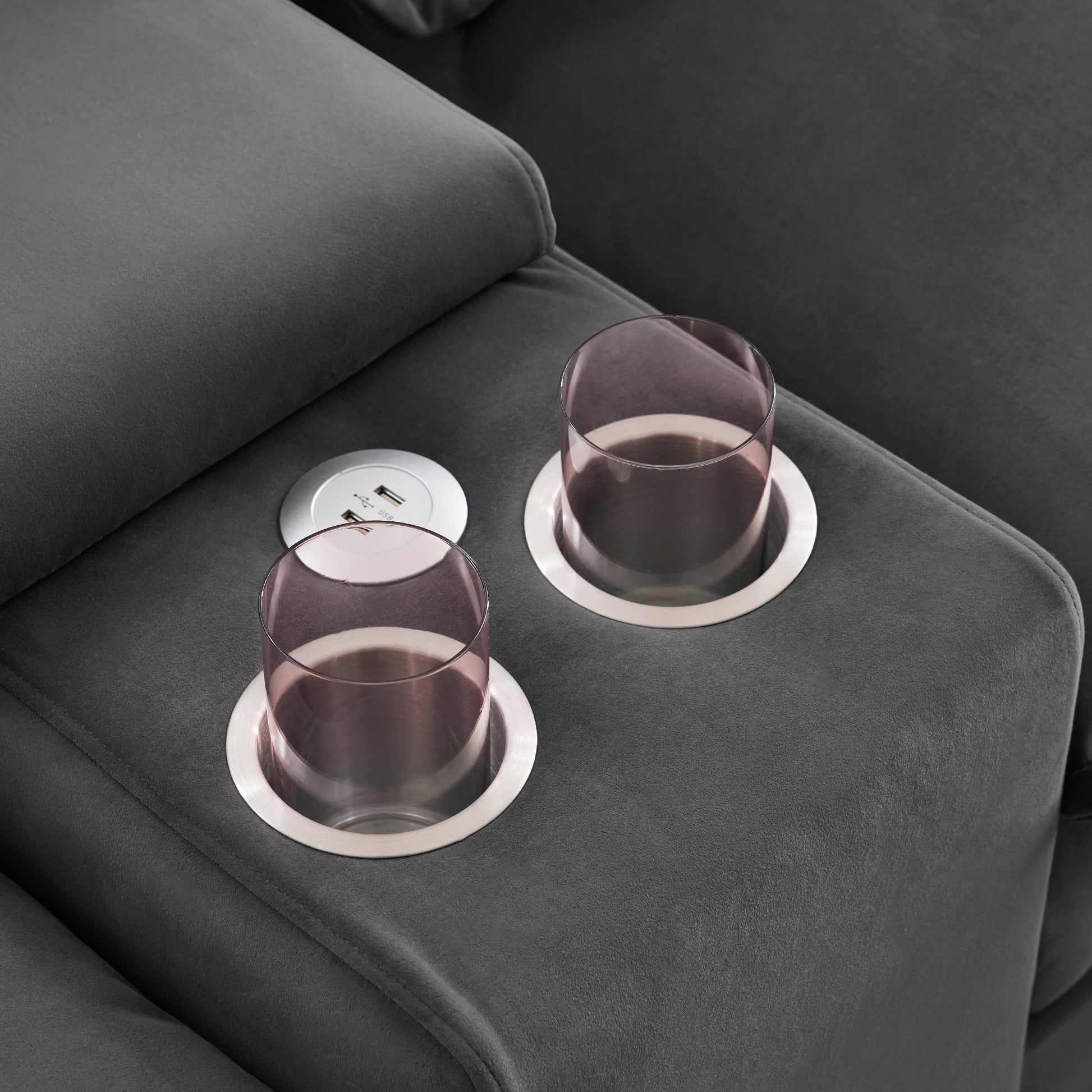 Dark grey fabric sofa armrest with integrated cup holders and USB charging port