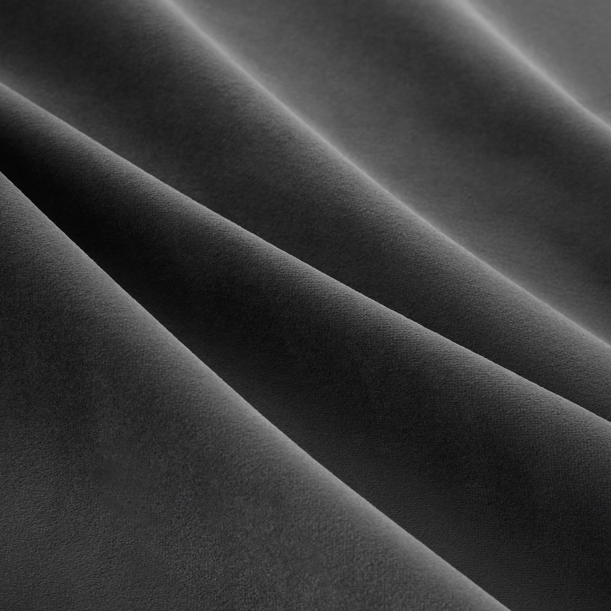 Closeup of dark gray velvet fabric with soft folds and a matte finish