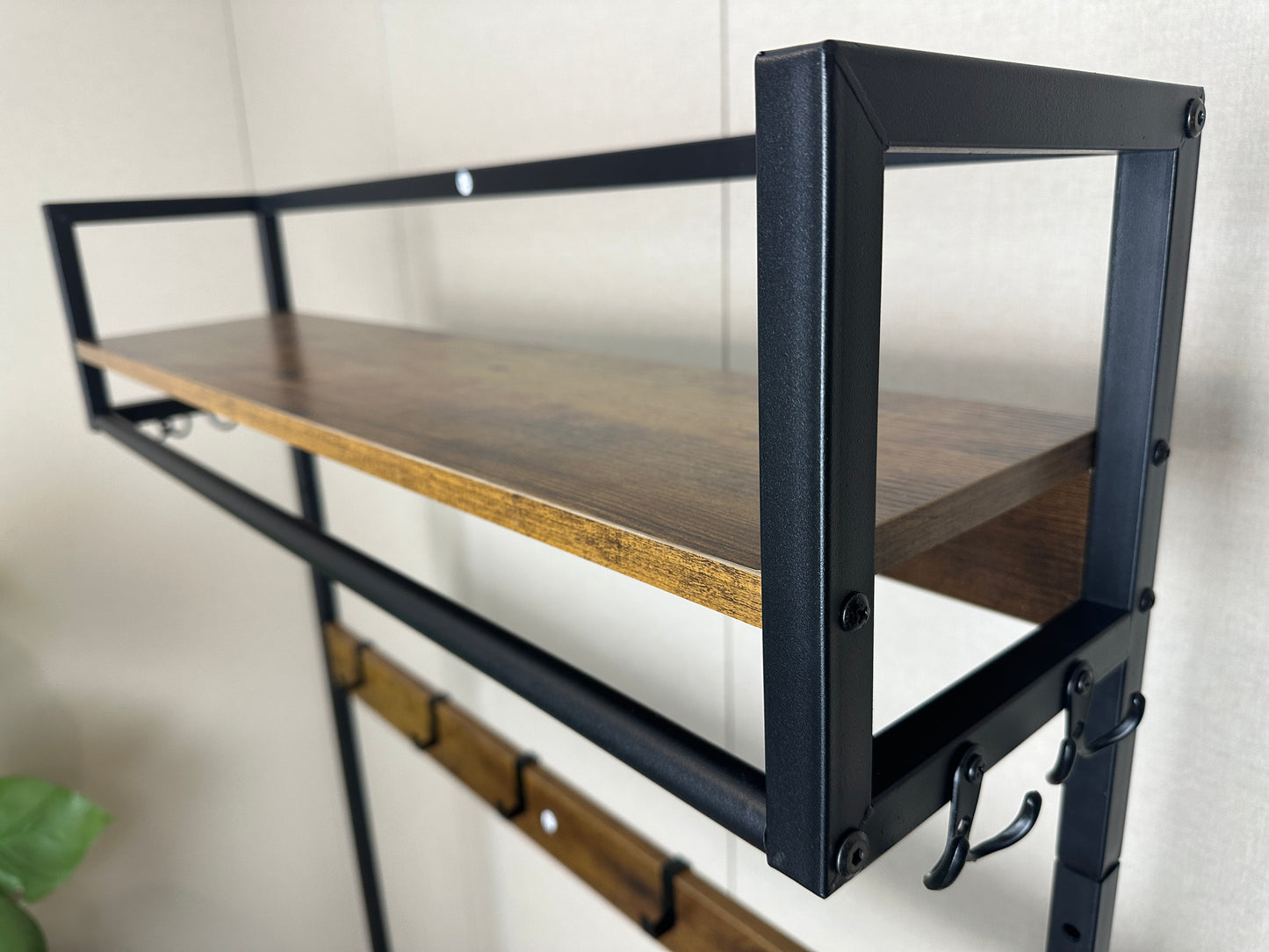 Rustic brown wood shelf with black metal frame featuring coat hooks for entryways